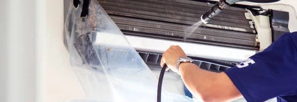 Technician servicing a split AC indoor unit in a Dubai apartment