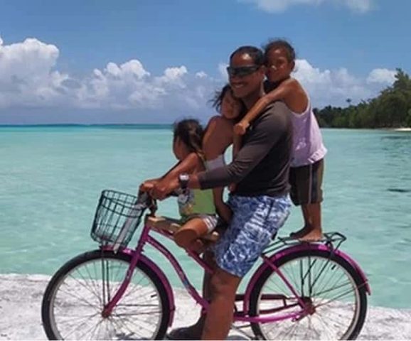 Un papa et ses enfants sur un vélo à Kauehi