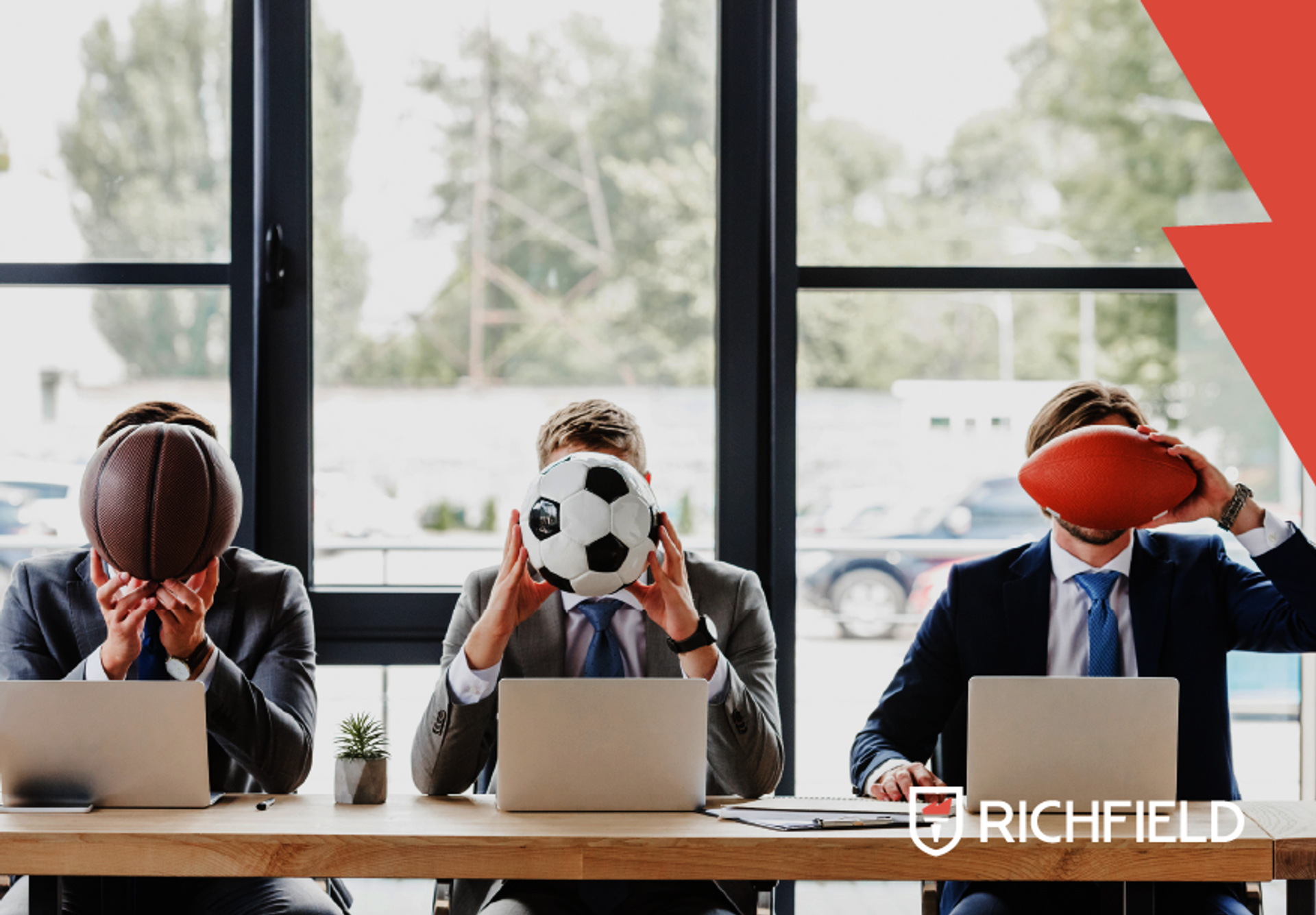 Men siting at a desk in an office setting with football, basketball and rugby balls. Richfield logo in bottom left corner.
