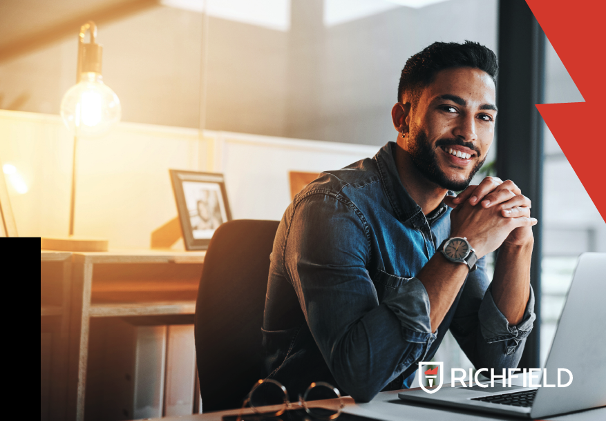 Young professional sitting behind a desk facing his computer.