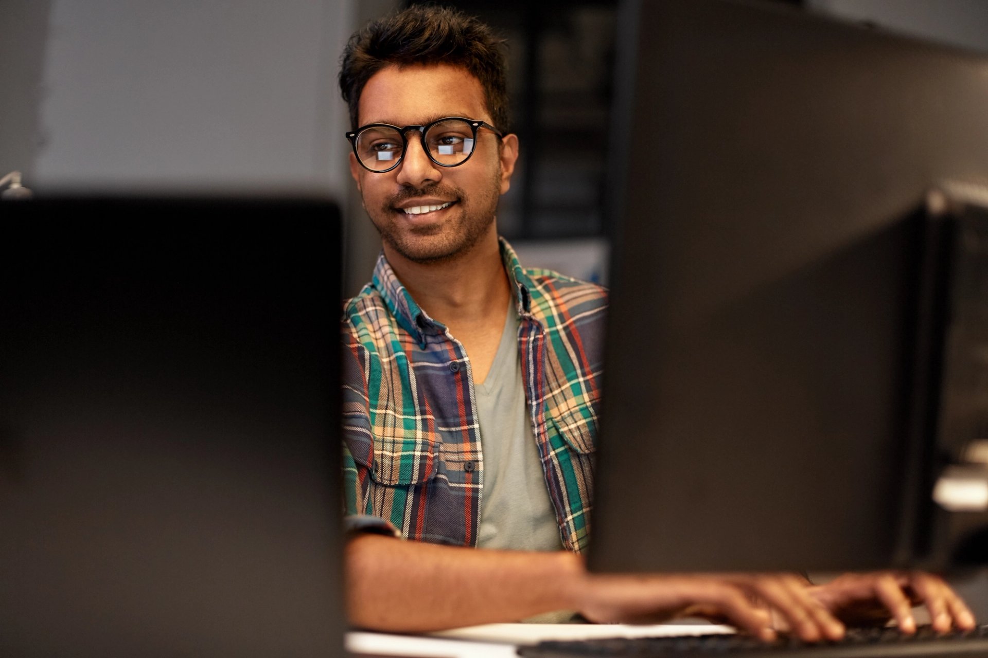 Man working on a laptop with coding language on the screen.