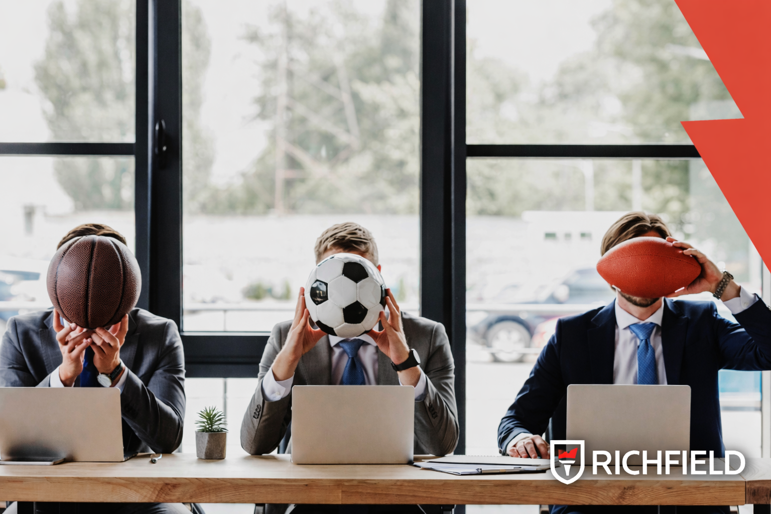 Men siting at a desk in an office setting with football, basketball and rugby balls. Richfield logo in bottom left corner.