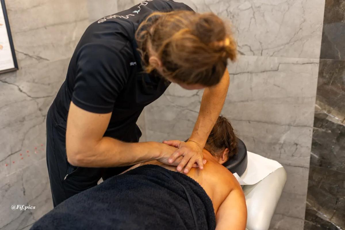 Person holding their upper back in discomfort