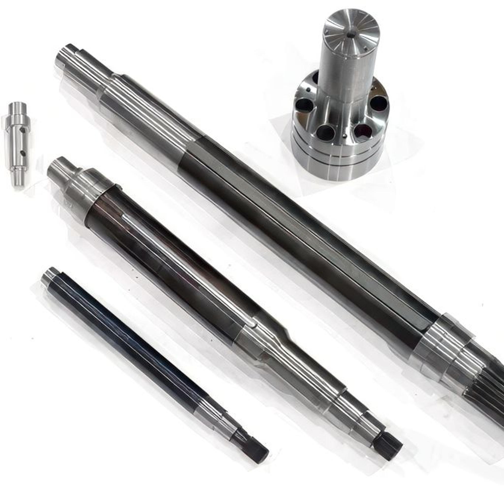 Machined industrial shafts, splined components and a flanged metal coupling displayed on a white surface.