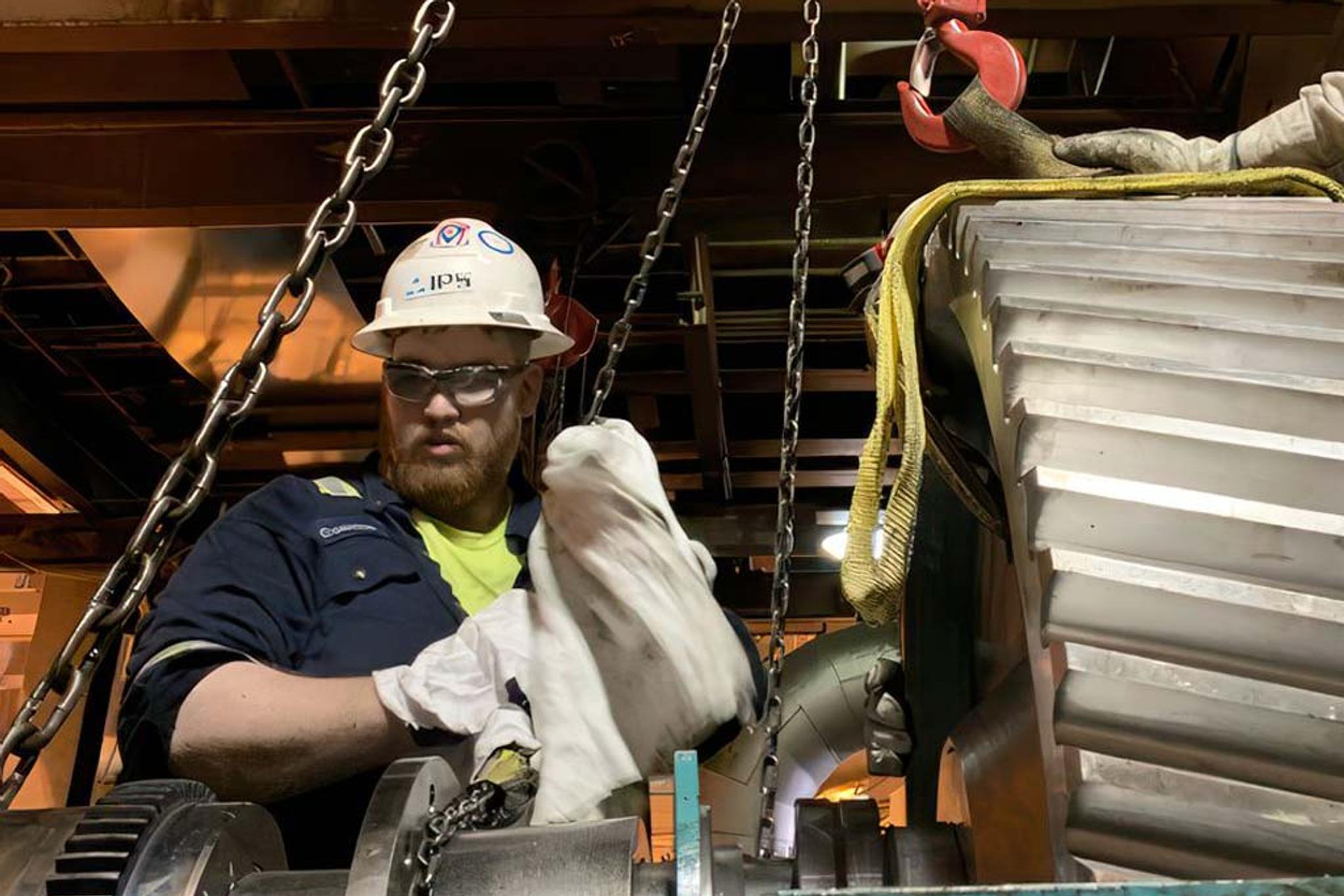 Un technicien IPS guide au palan un rotor de moteur électrique pendant une opération de levage.