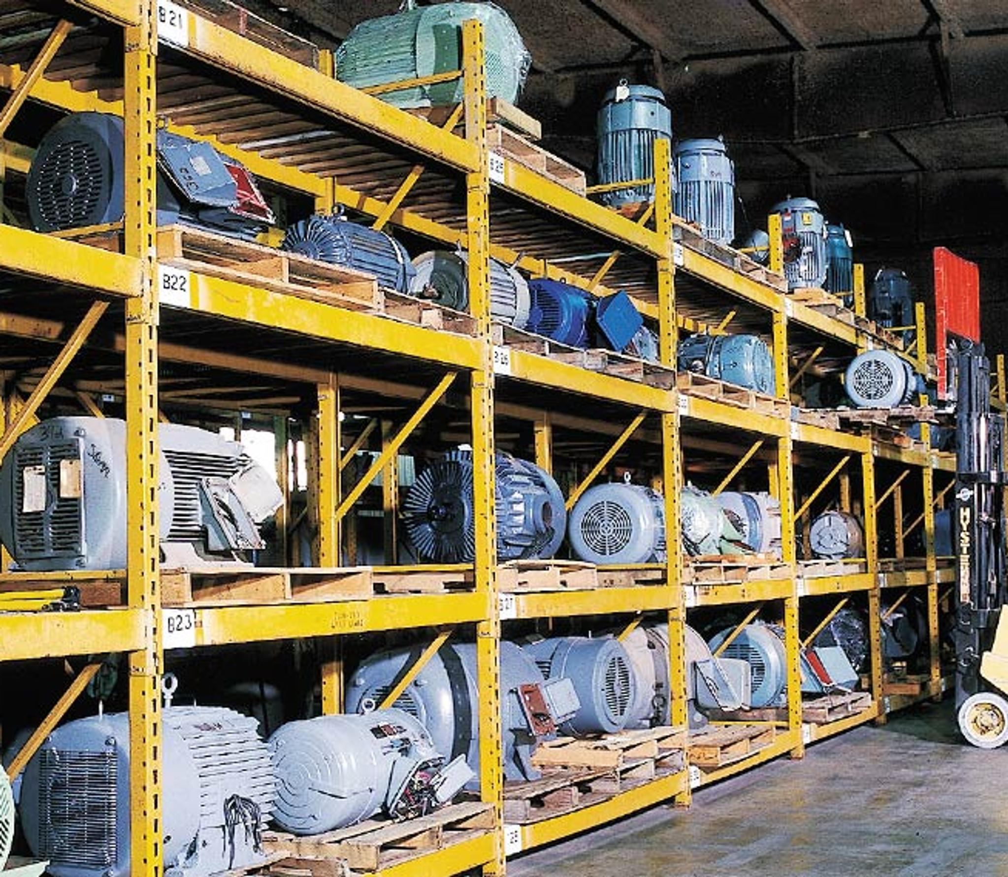 Un cariste déplace des moteurs électriques stockés sur des rayonnages industriels.