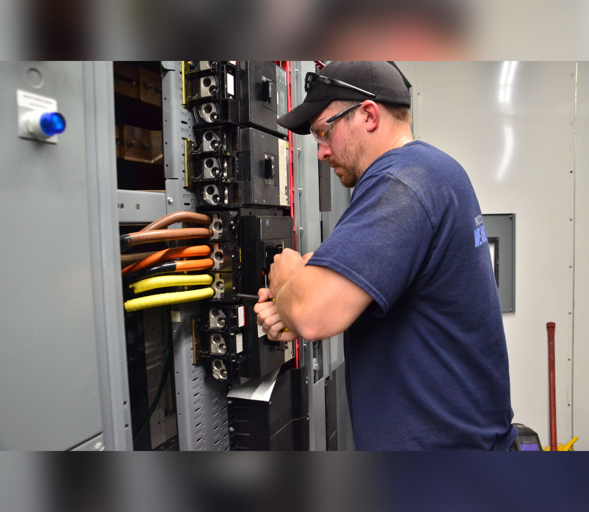 Un technicien resserre les connexions d’un disjoncteur dans une armoire électrique industrielle.