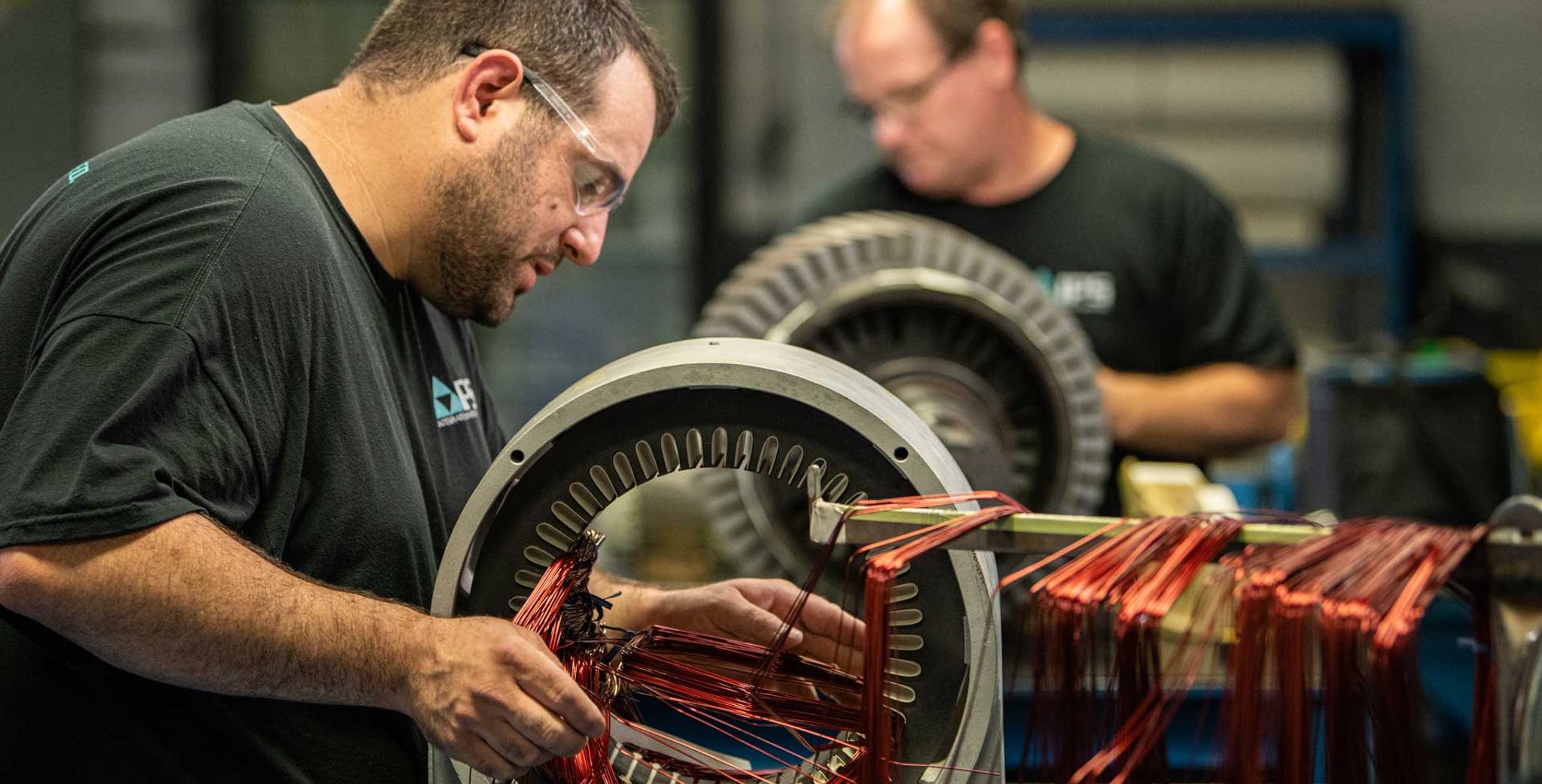 Technicians install copper windings in large electric motor stators at an IPS service center.