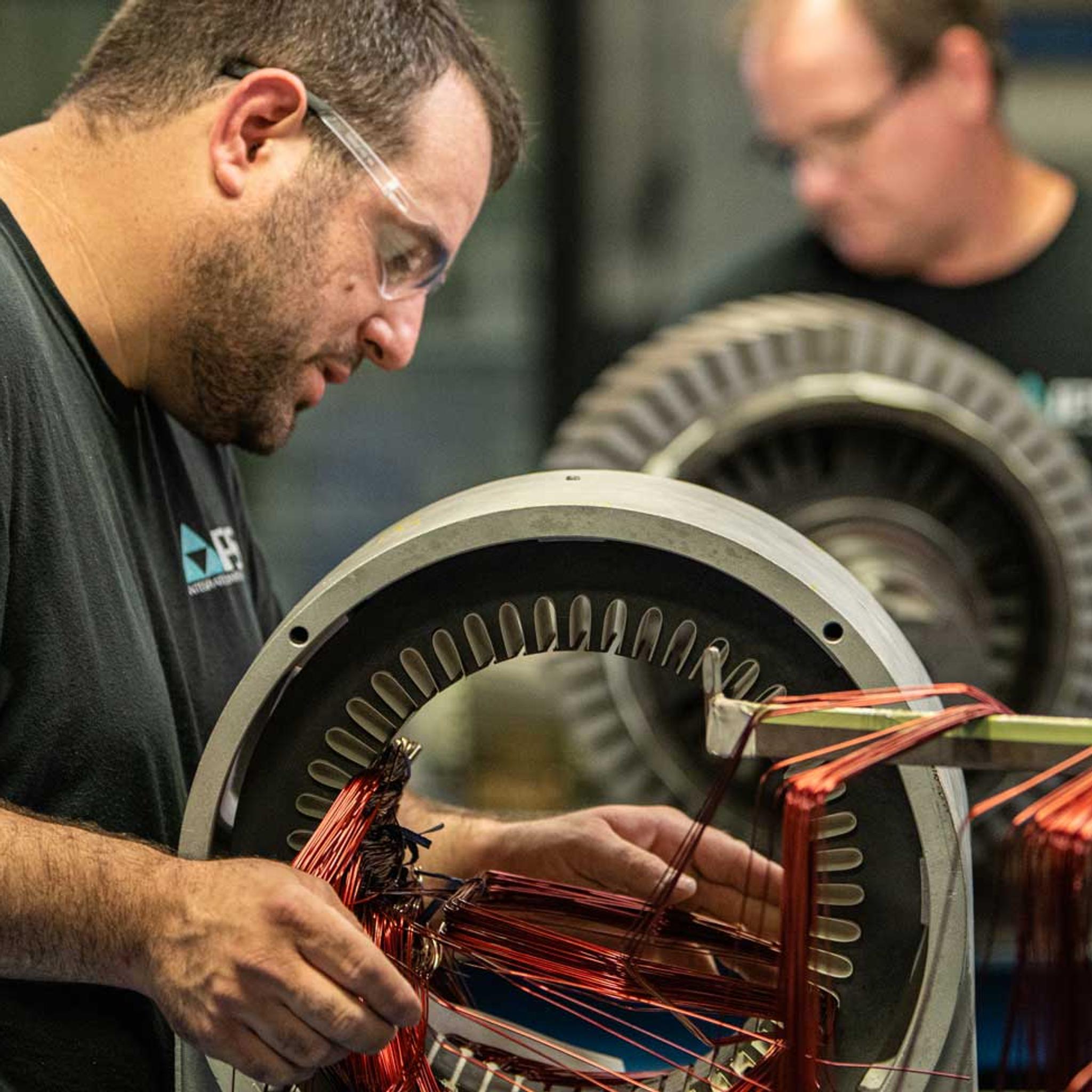 Technicians install copper windings in large electric motor stators at an IPS service center.