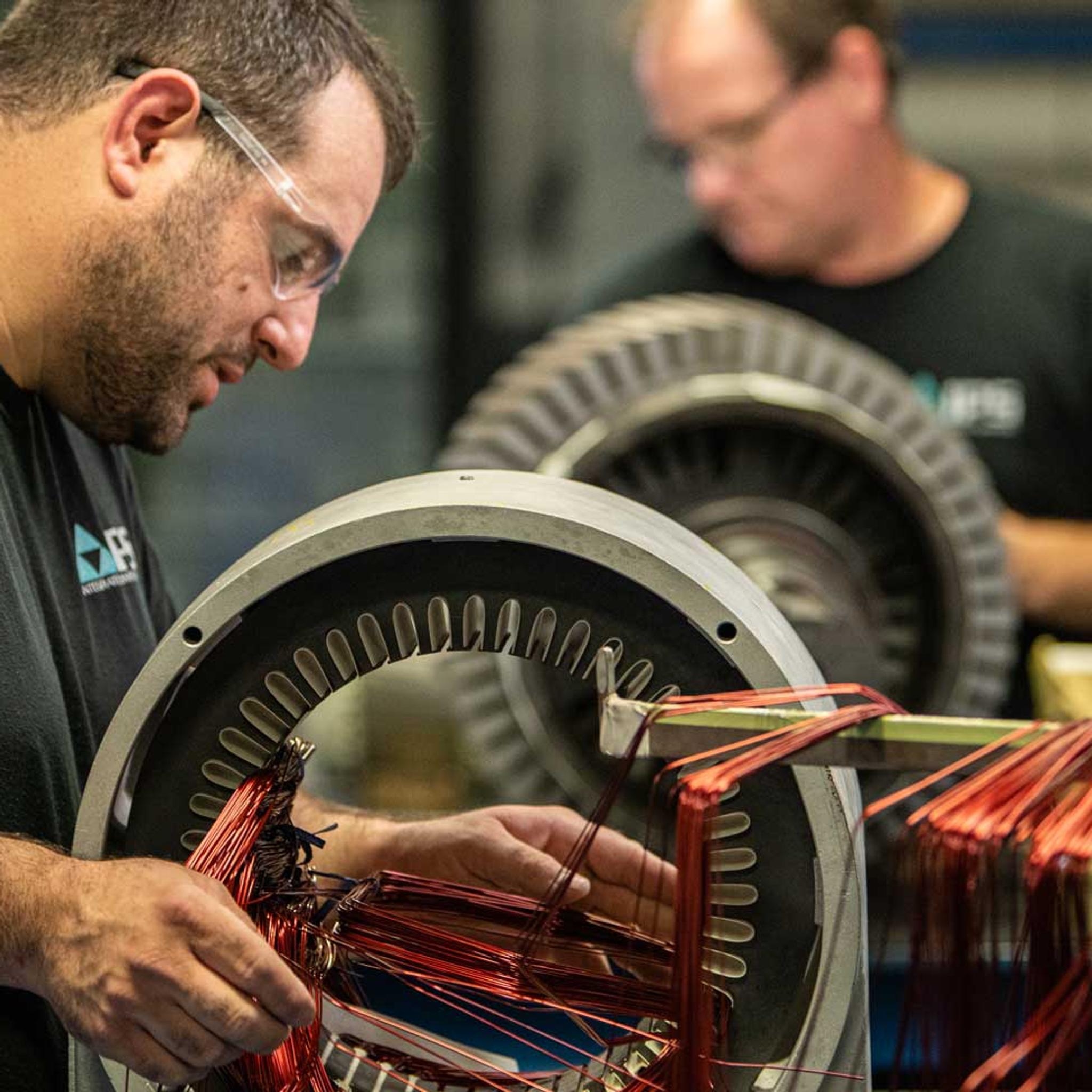 Technicians install copper windings in large electric motor stators at an IPS service center.