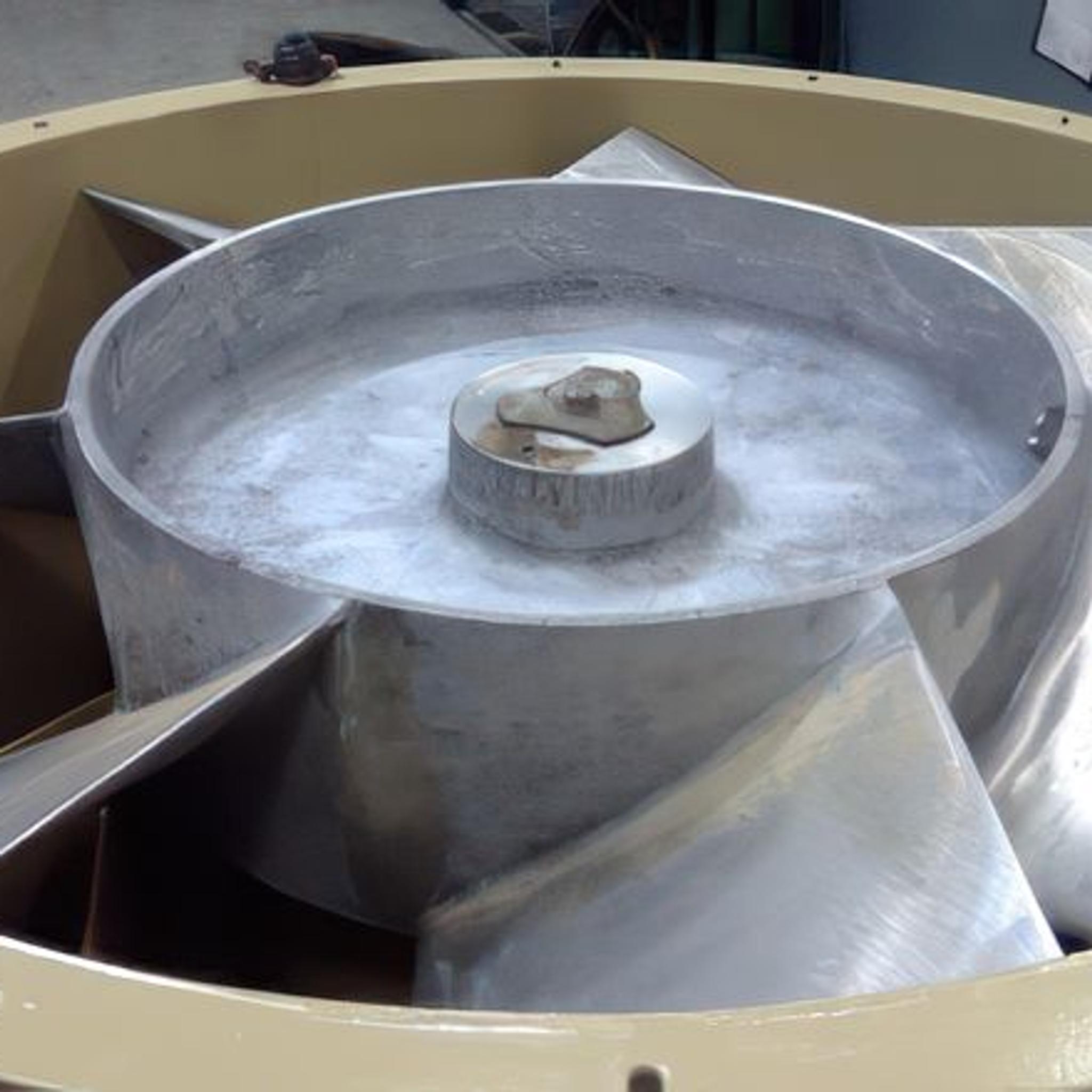 Large industrial fan impeller with curved metal blades inside a circular housing