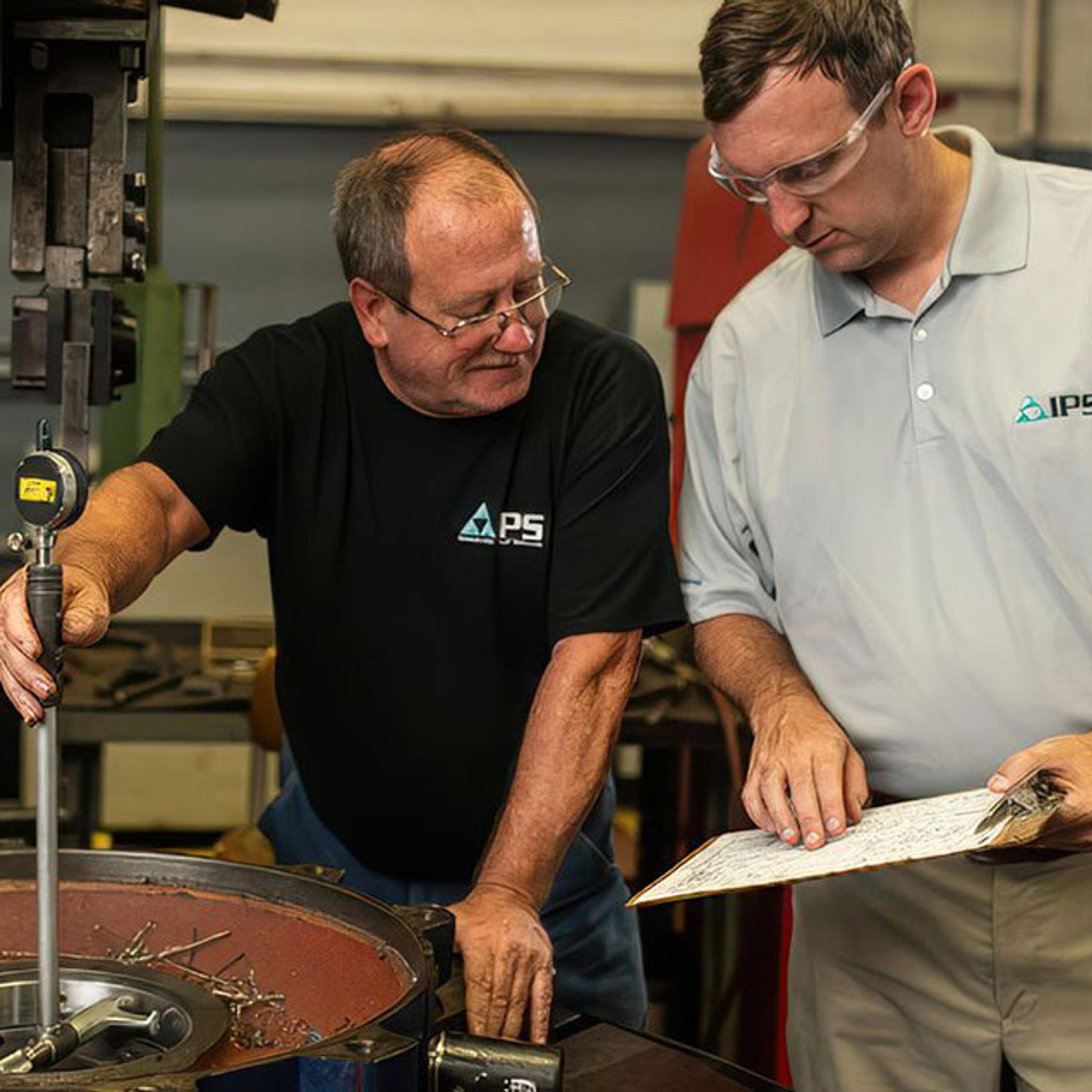 IPS technicians inspect a large motor housing with a bore gauge and technical drawing.