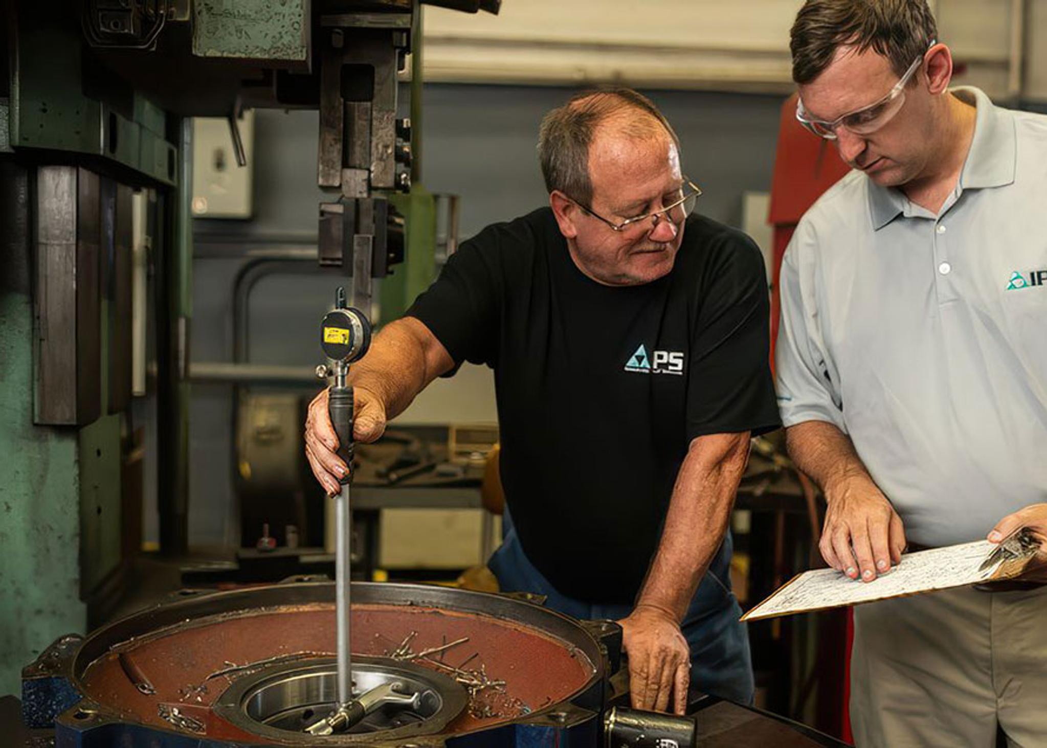 IPS technicians inspect a large motor housing with a bore gauge and technical drawing.
