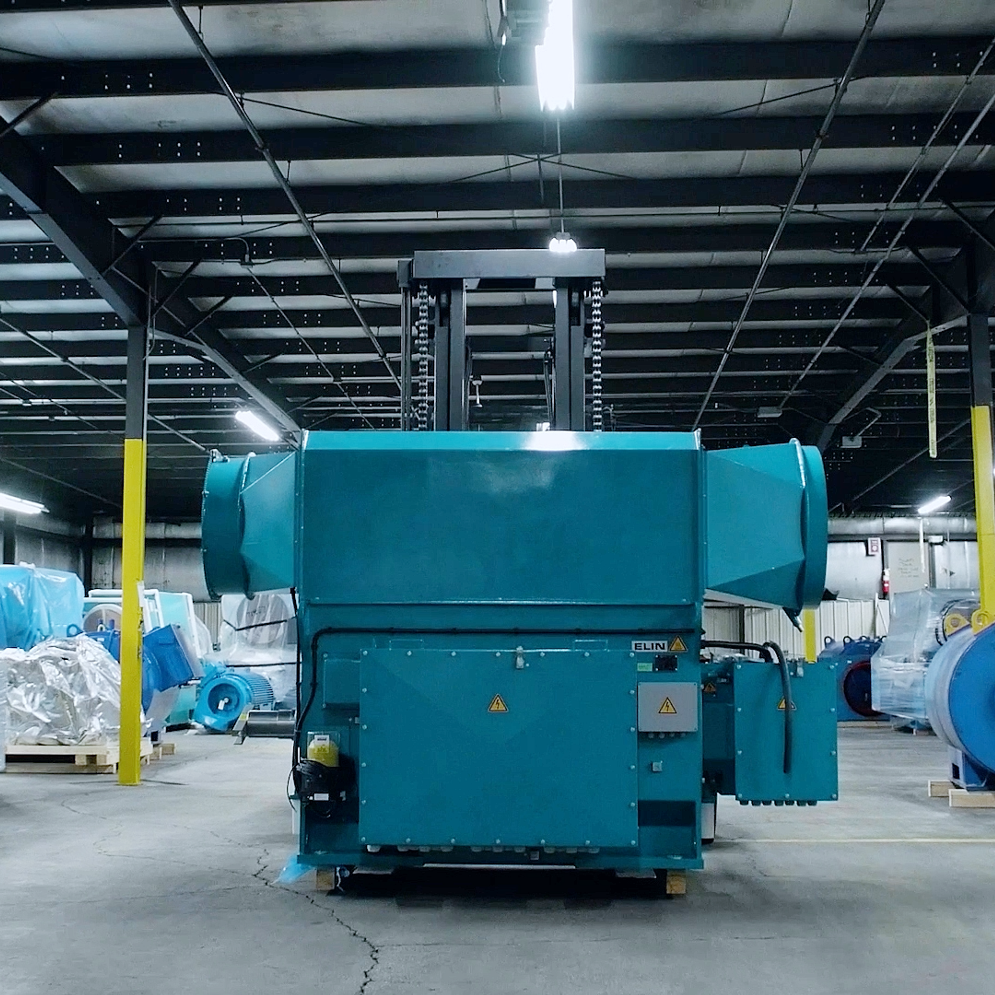 Large industrial electric motor positioned beneath an overhead lifting frame in a service facility.
