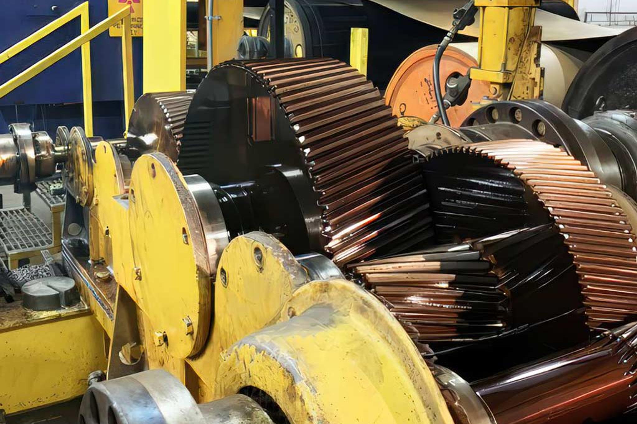 Large motor rotors with copper windings mounted in yellow industrial repair equipment