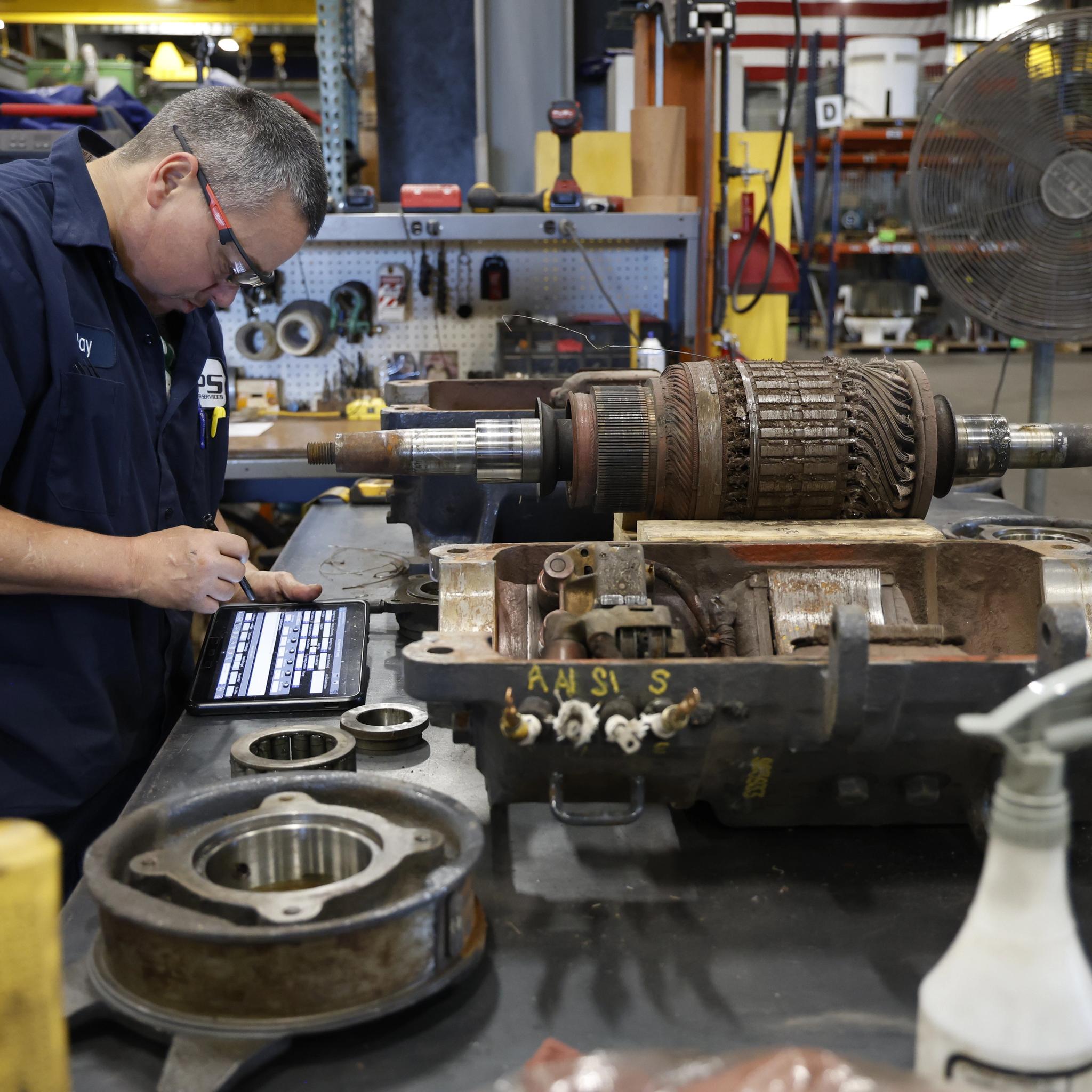 IPS technician records inspection data for a disassembled motor rotor on a tablet.