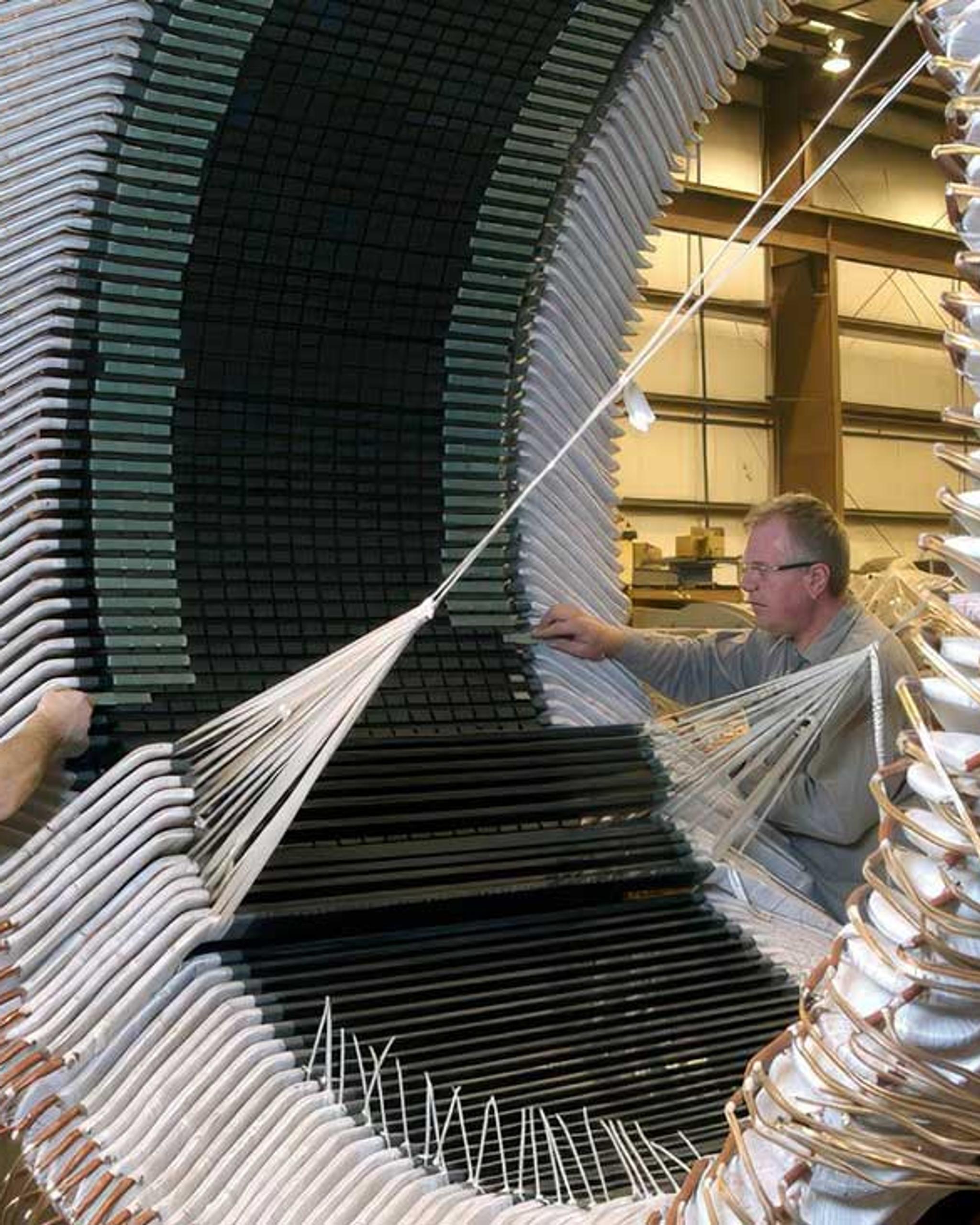 Técnicos instalan bobinados aislados en el estator de un gran generador industrial.