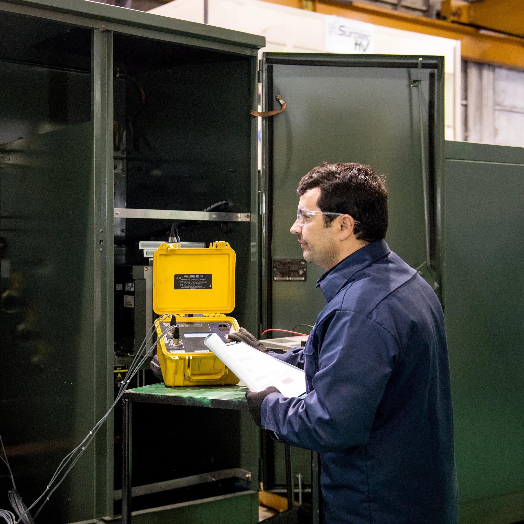 Technician uses portable test equipment to inspect switchgear in an industrial service shop.