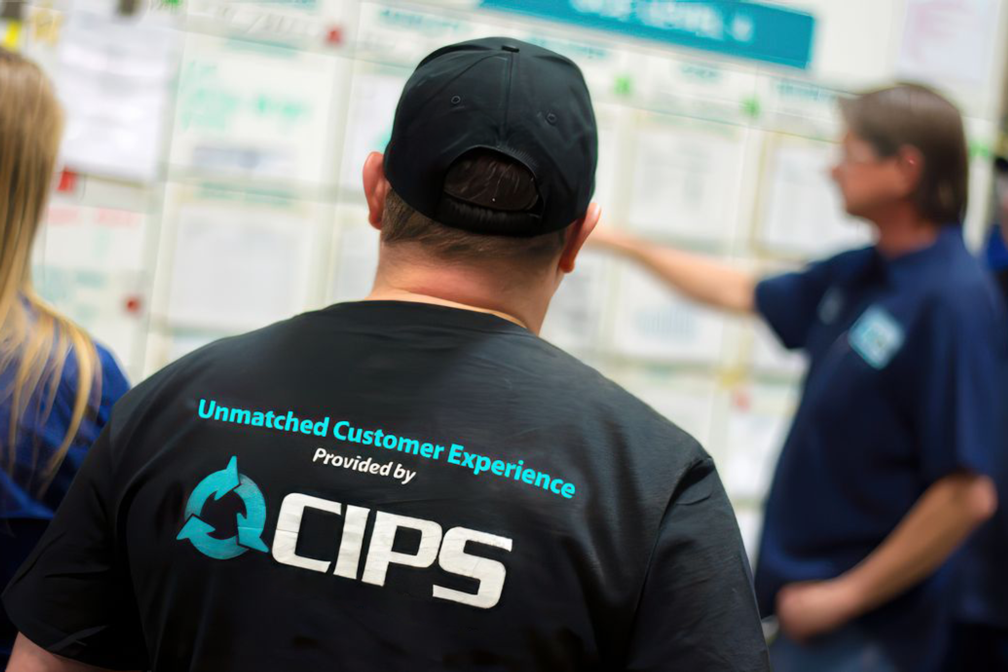 CIPS employee attends a team briefing in front of a planning board.