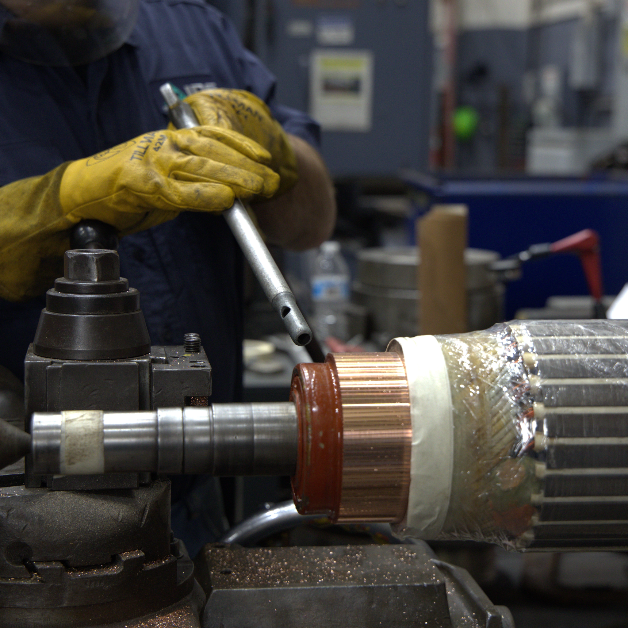 Technicien usinant le collecteur en cuivre d’un rotor de moteur électrique sur un tour.