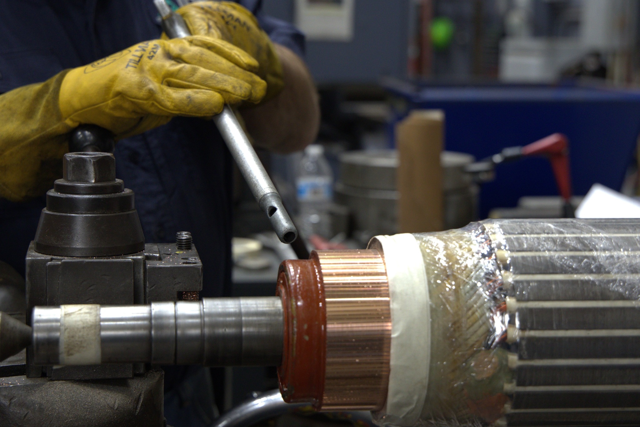 Técnico con guantes ajusta el rotor de un motor eléctrico montado en un torno.
