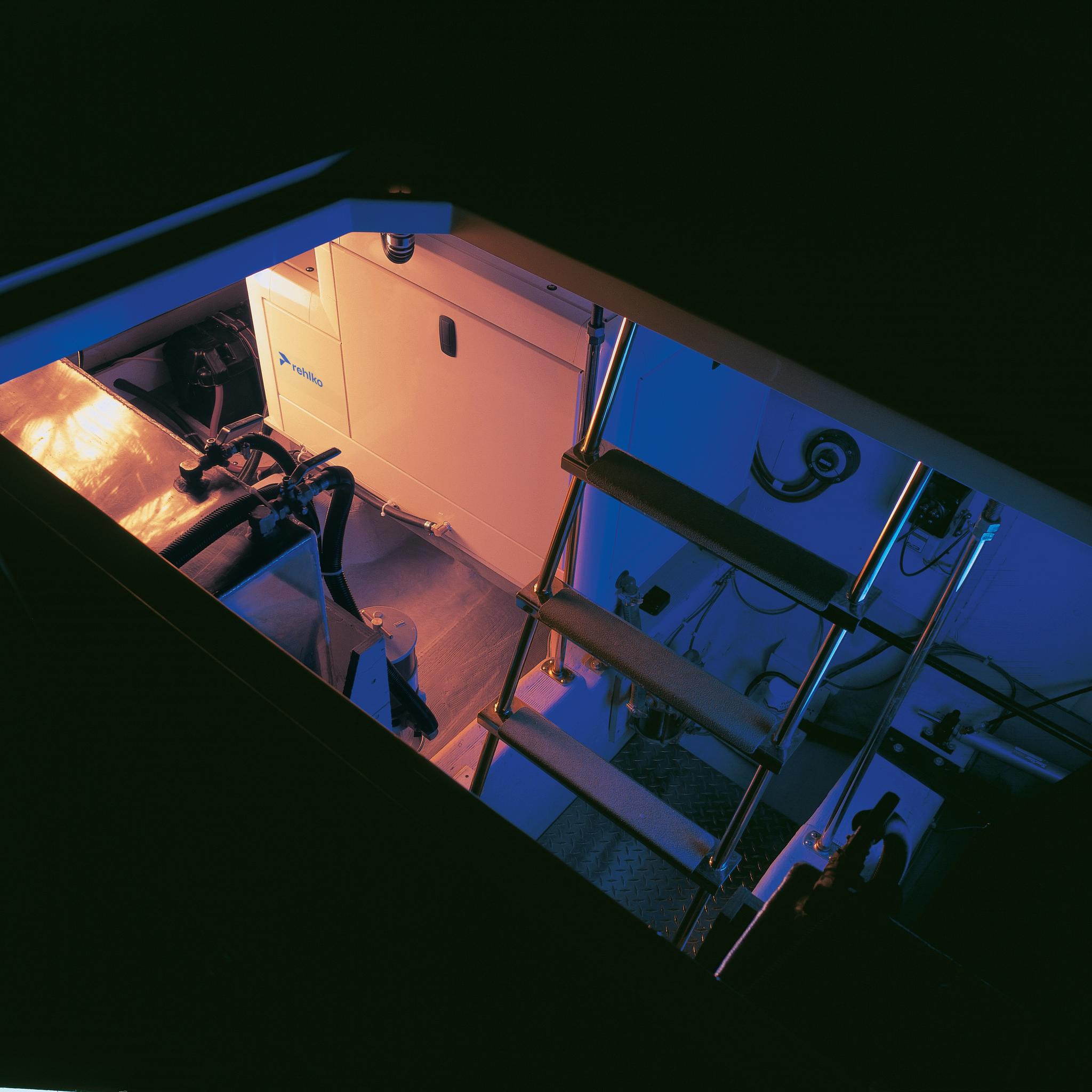 Industrial generator and fuel system installed below deck beside a metal access ladder.