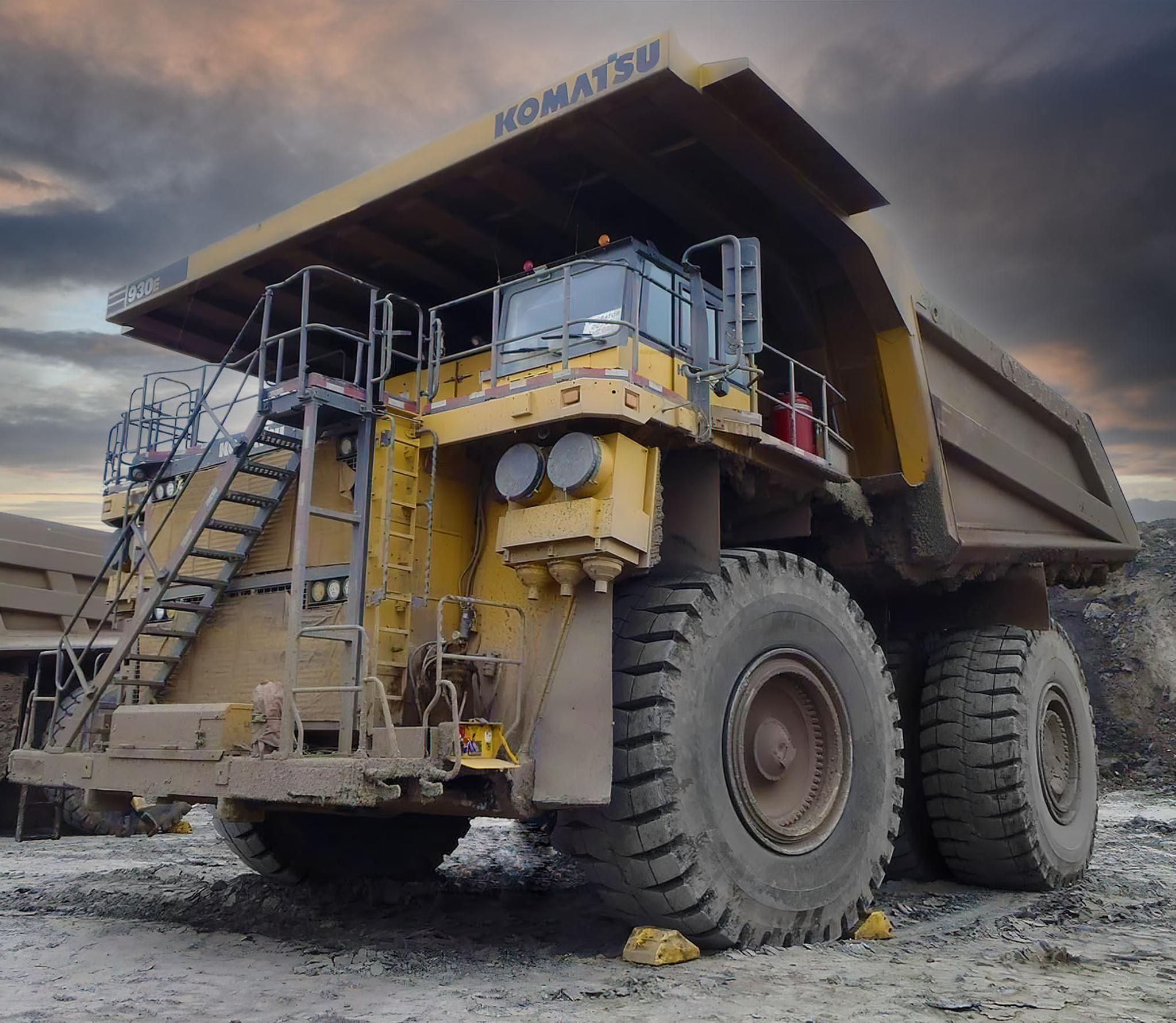 Camion-benne minier Komatsu 930E stationné dans une carrière sous un ciel orageux.