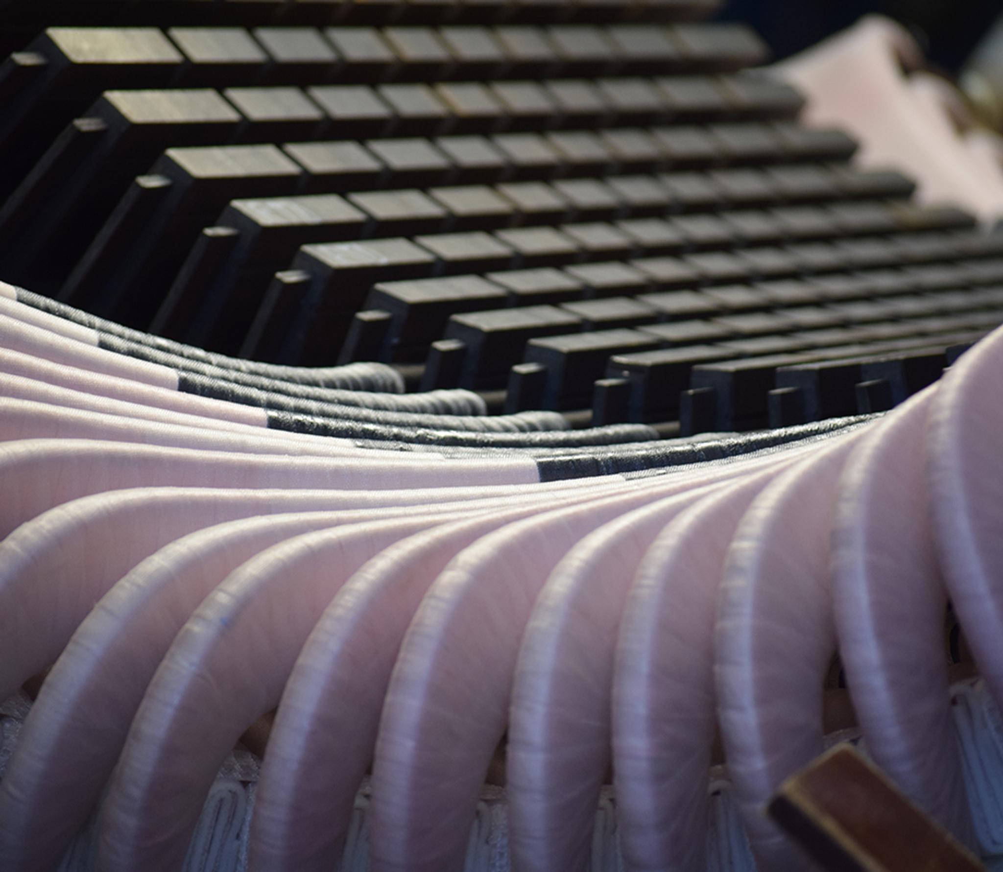 Gros plan sur les bobinages isolés et les cales d’un stator de générateur électrique.