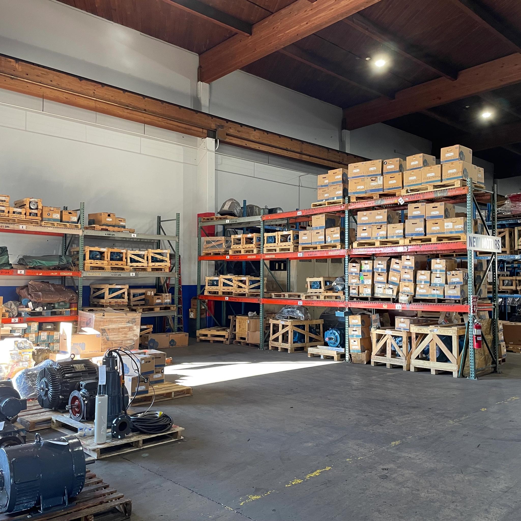 Electric motors and boxed parts stored on pallets and warehouse shelving.