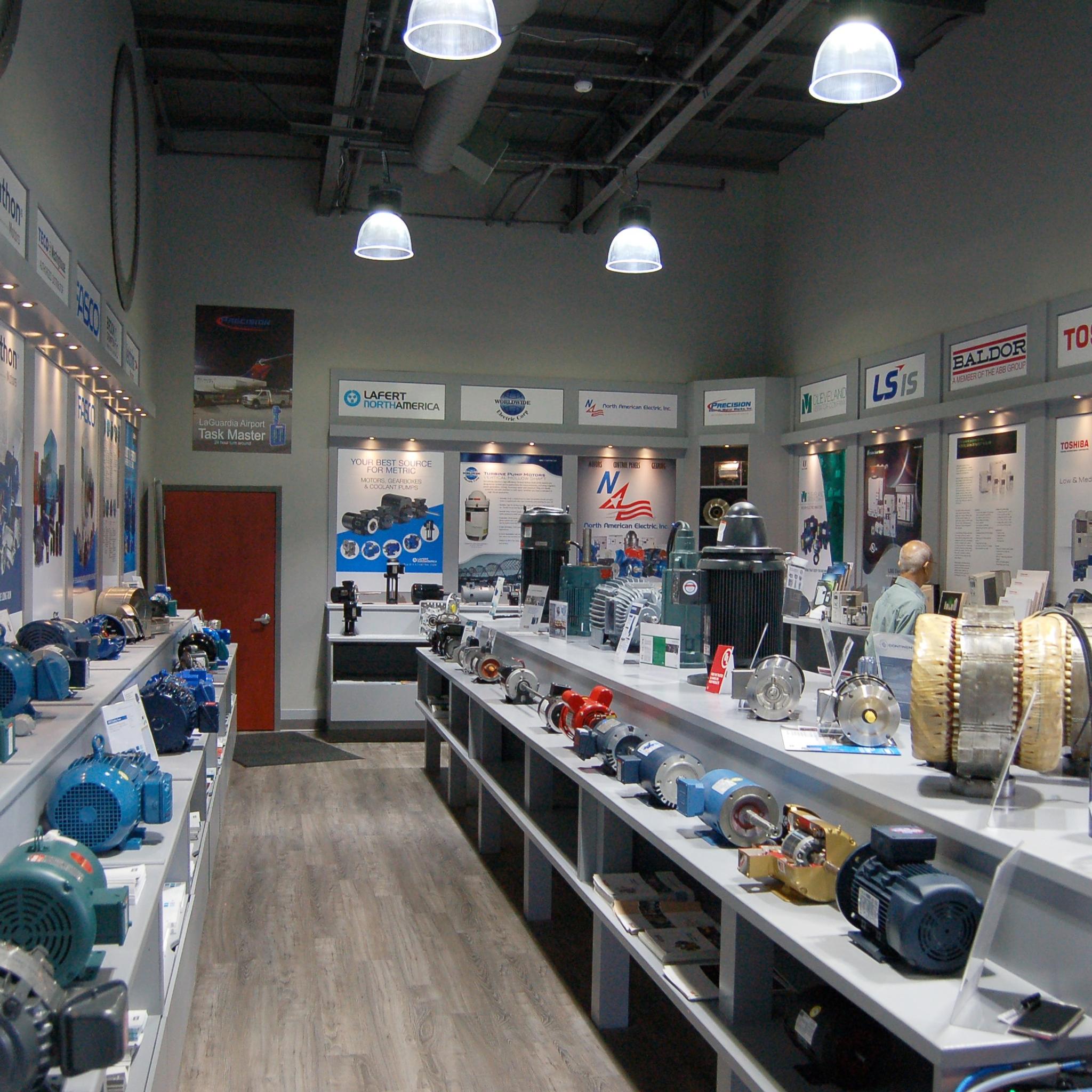 Industrial showroom displays electric motors, generators and motor components on long counters.