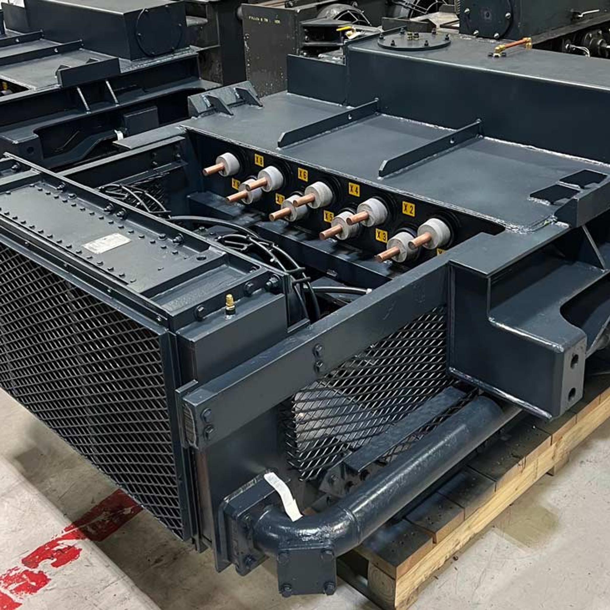 Industrial transformer with six high-voltage bushings and cooling radiators on a wooden pallet.