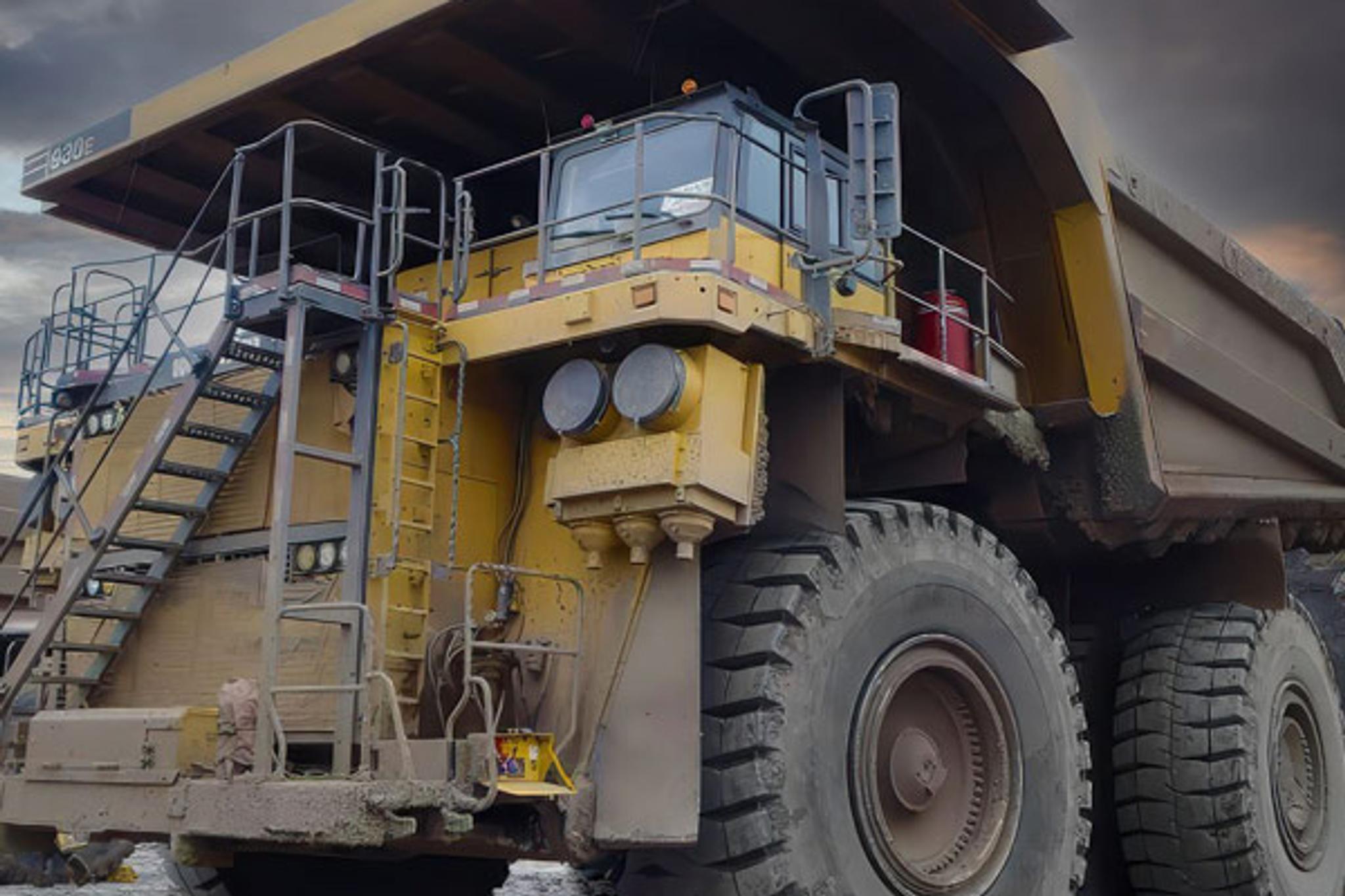 Large Komatsu mining haul truck parked at an industrial site under cloudy skies.