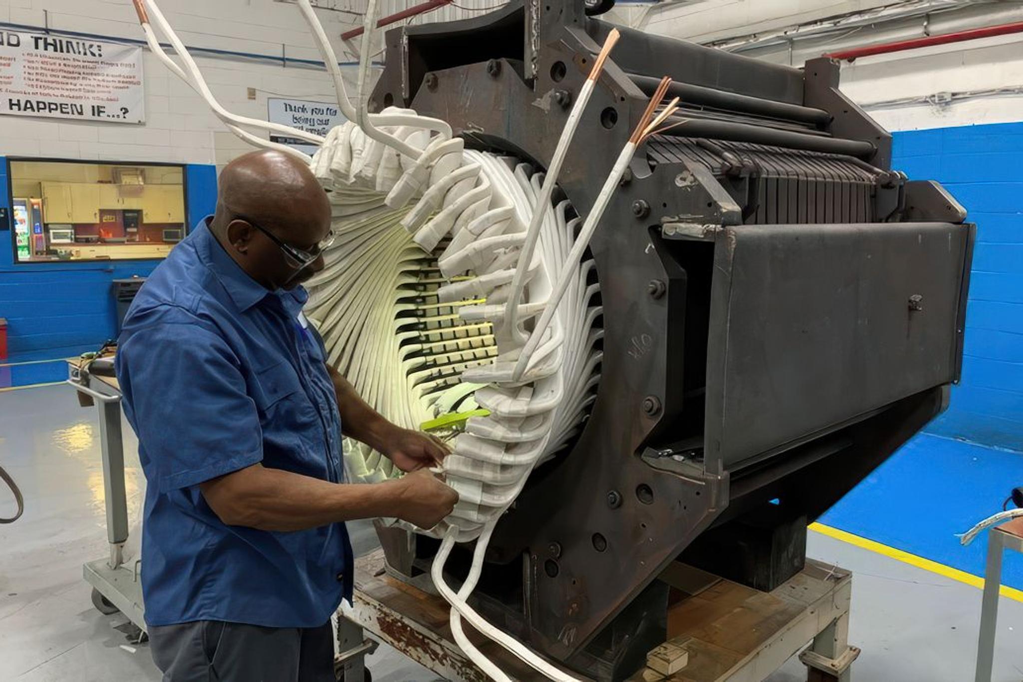 Technician installs insulated windings in a large industrial generator stator.