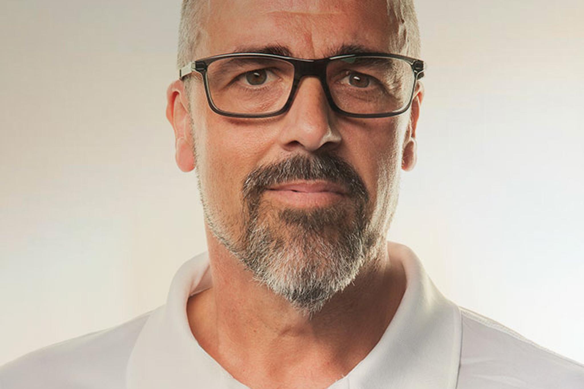 Headshot of a man wearing glasses and a white MDL polo shirt.