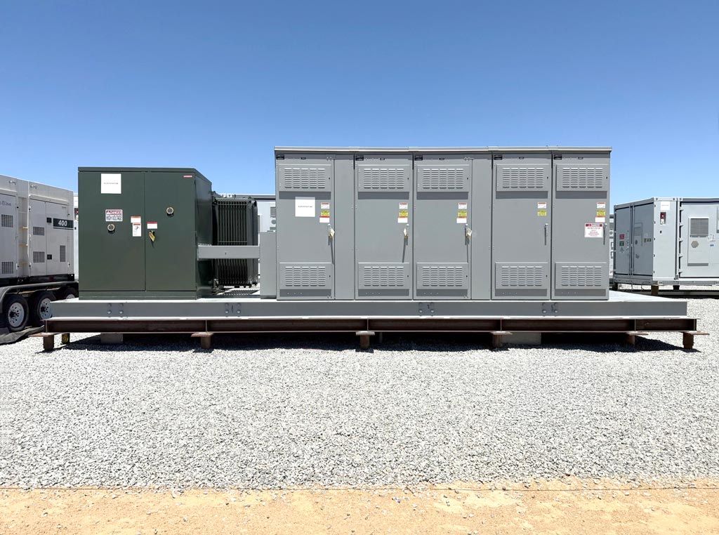 Outdoor lineup of industrial switchgear cabinets and a transformer mounted on a steel platform.