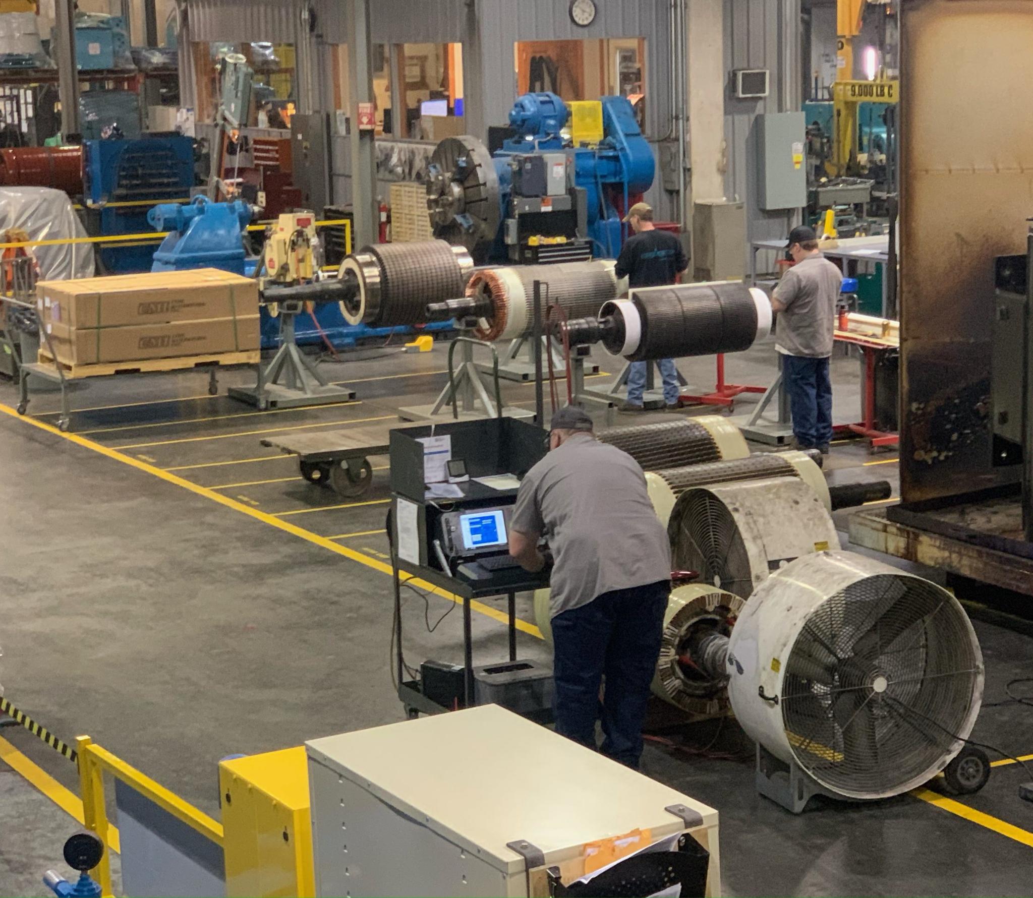 Techniciens inspectant et réparant des rotors de moteurs électriques dans un atelier industriel.