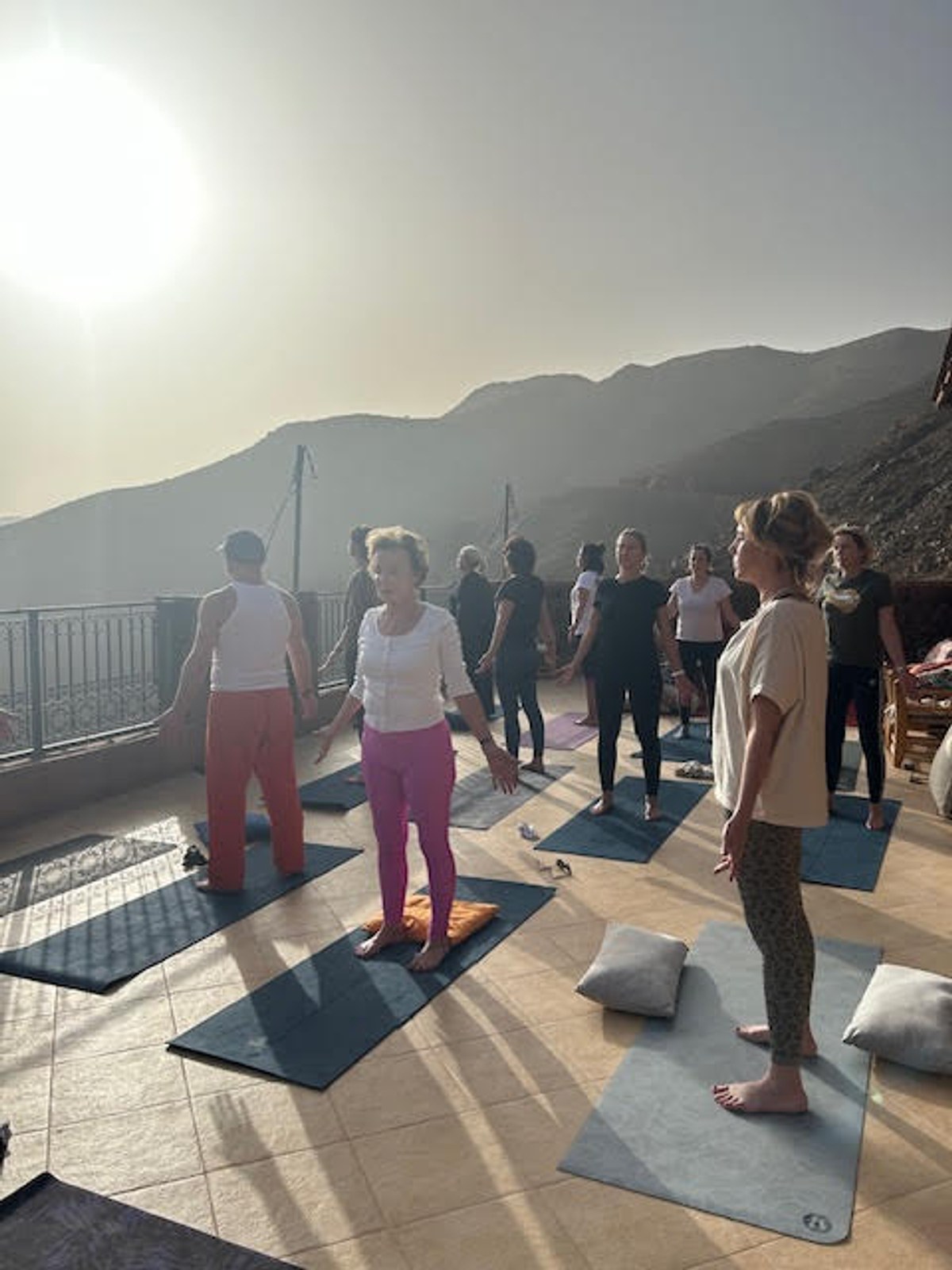 Séance de yoga en groupe sur une terrasse face aux montagnes au Maroc