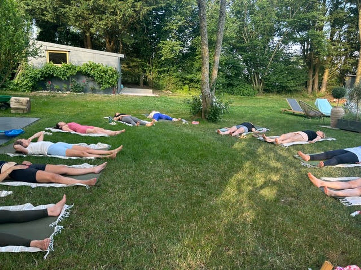 Un groupe allongé sur les tapis pendant une séance dans un jardin