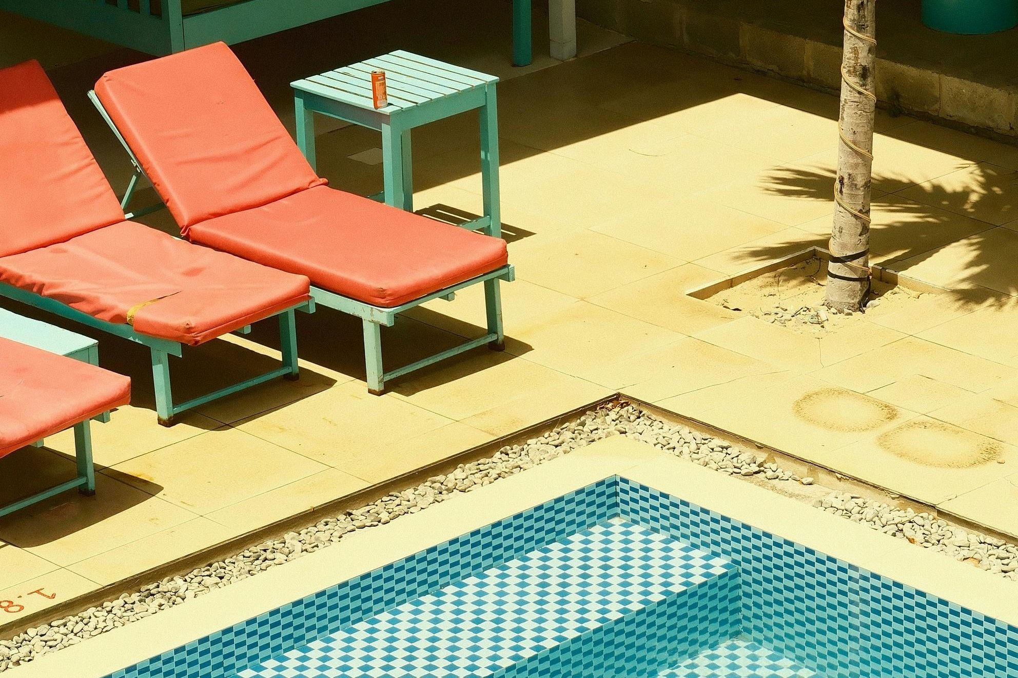 Some colourful fold-out chairs by an outdoor pool