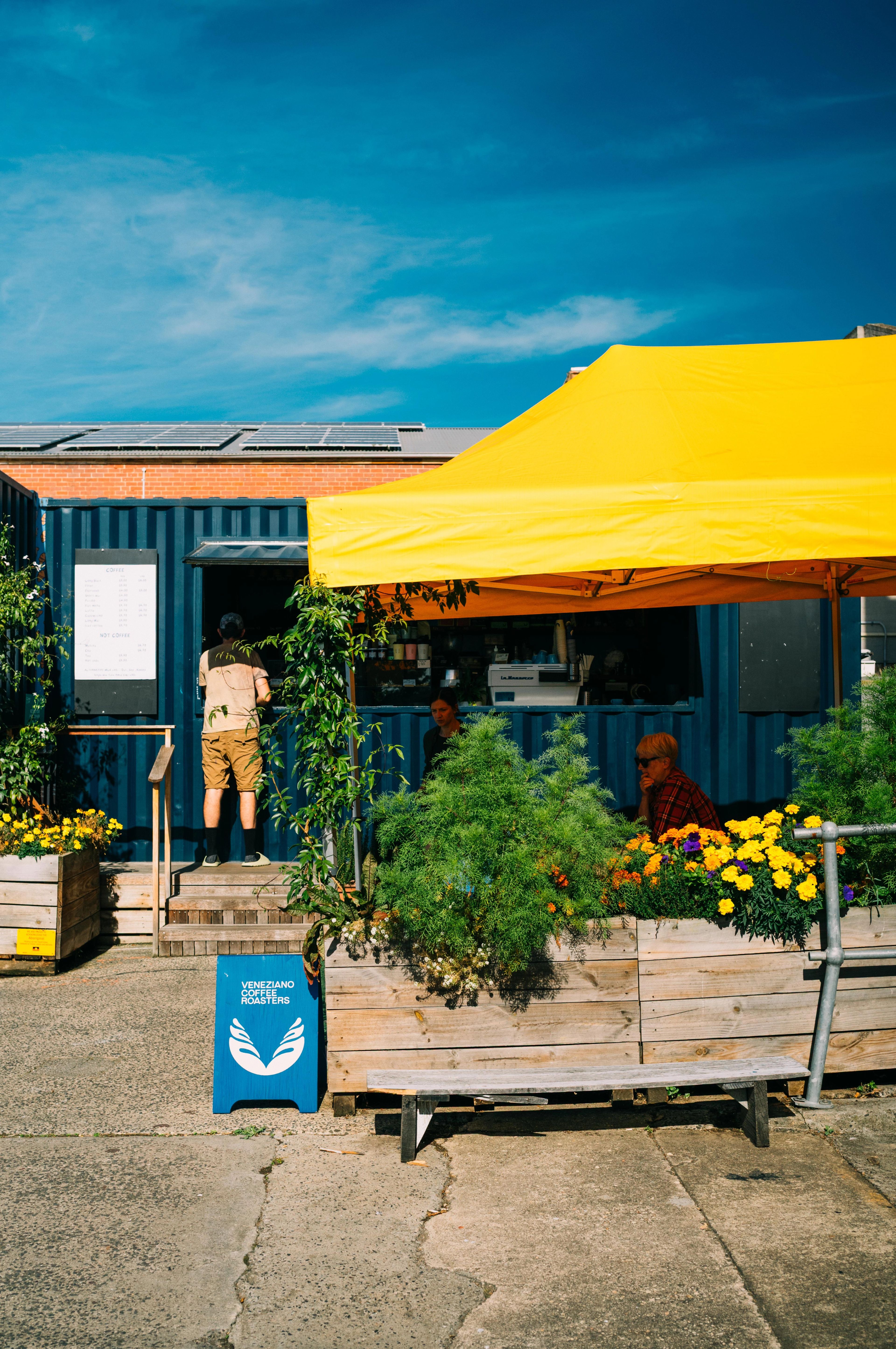 A coffee and a pastry side by side on a wooden picnic bench