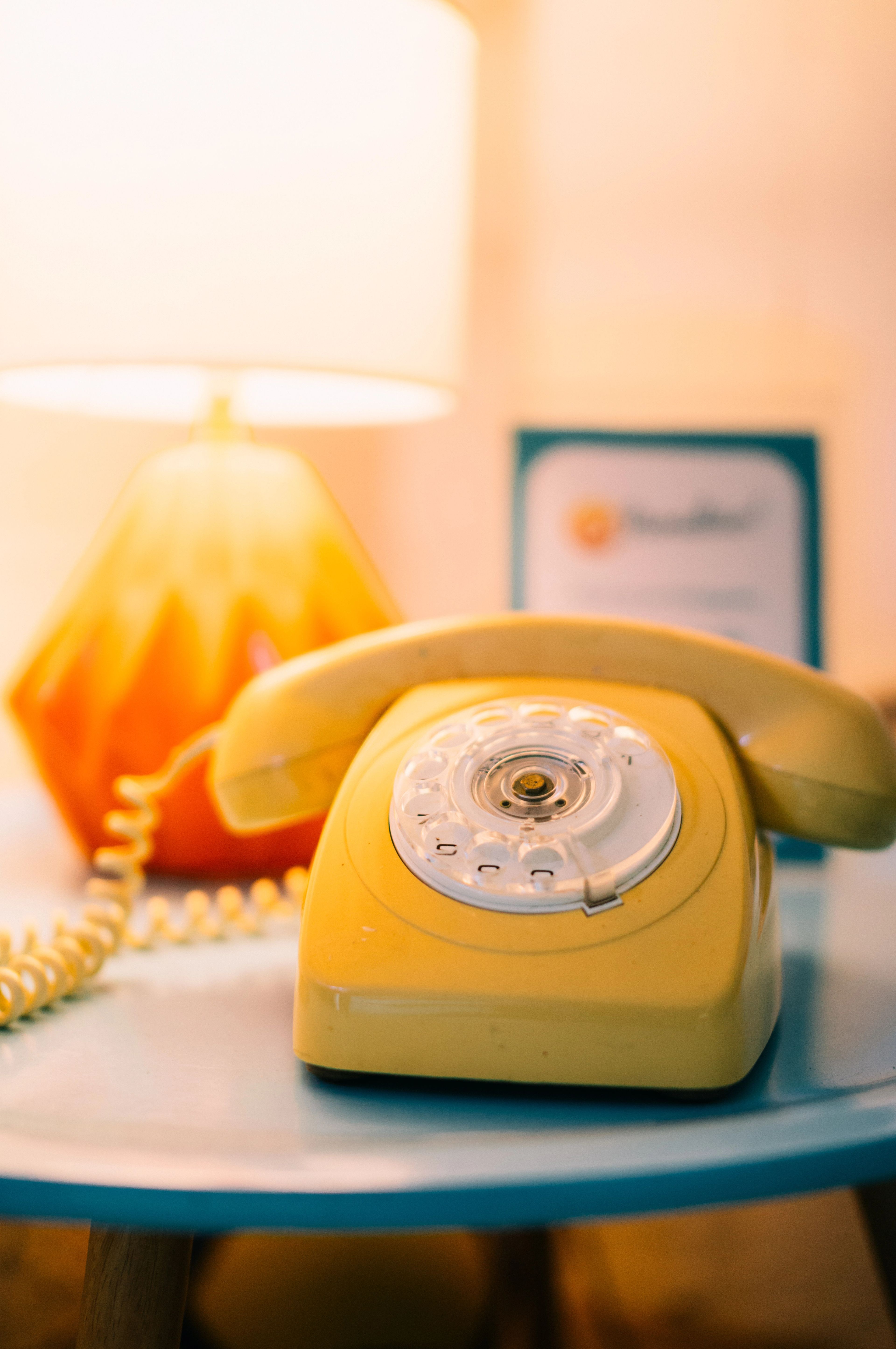 A brightly coloured telephone by a lamp