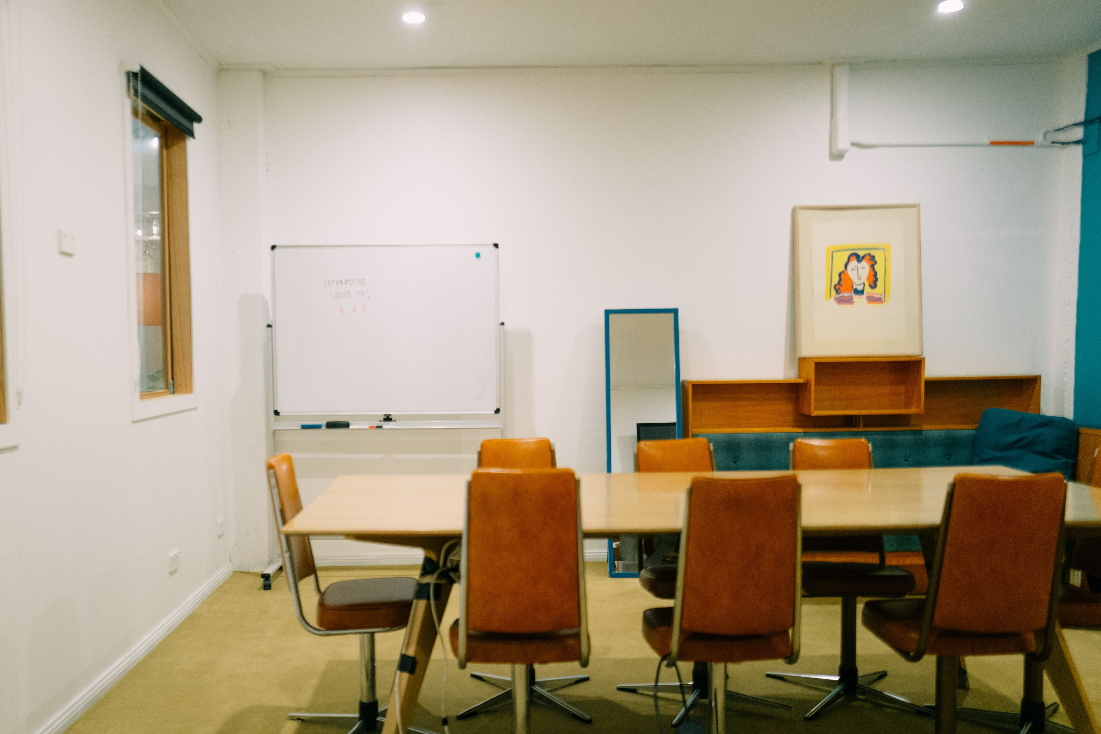 A brightly lit room with a long table and whiteboard