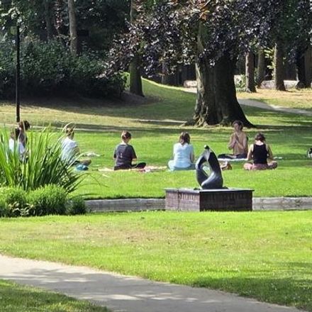 Deelnemers die samen yoga doen in het gras van de Engelse tuin