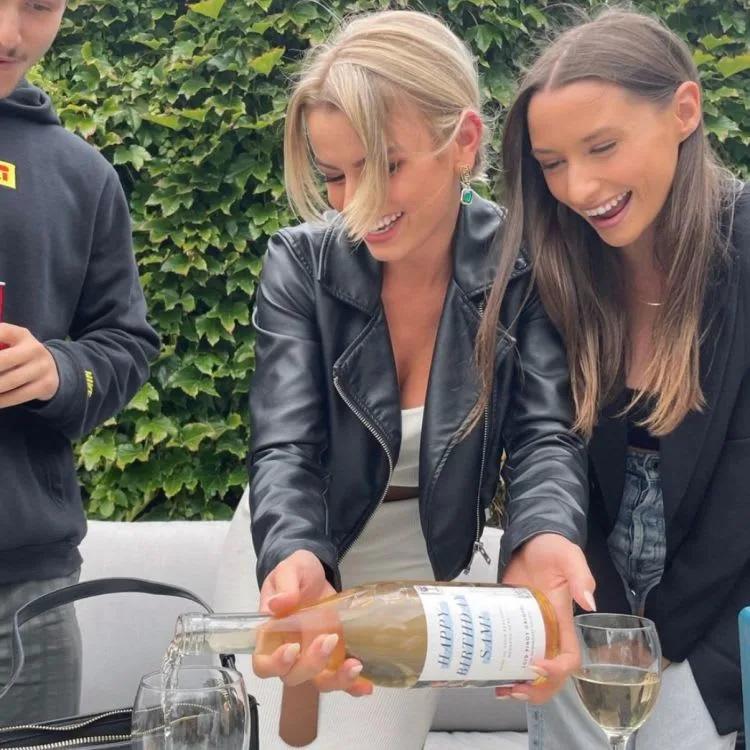 person holding personalised alcohol bottle and two glasses