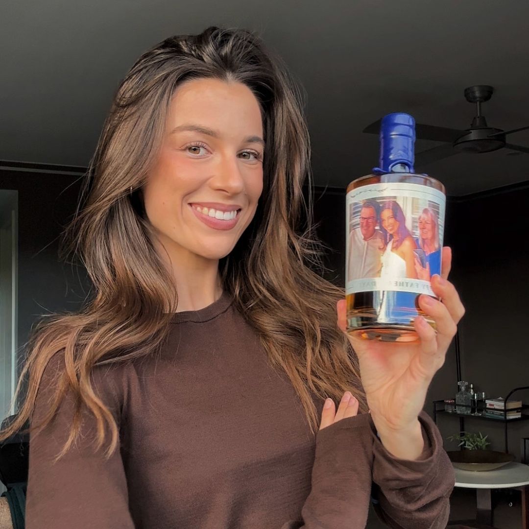 person holding personalised alcohol bottle and two glasses