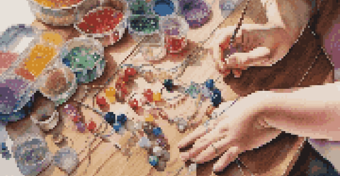 Children's hands threading colorful beads onto elastic string to create bracelets, with various crafting supplies on a wooden table.