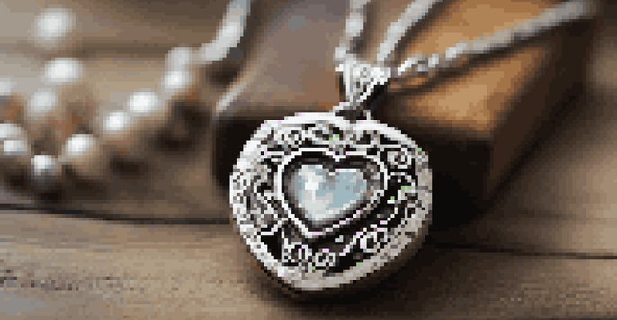 A custom necklace with a heart-shaped pendant and initials, beautifully lit on a wooden table.