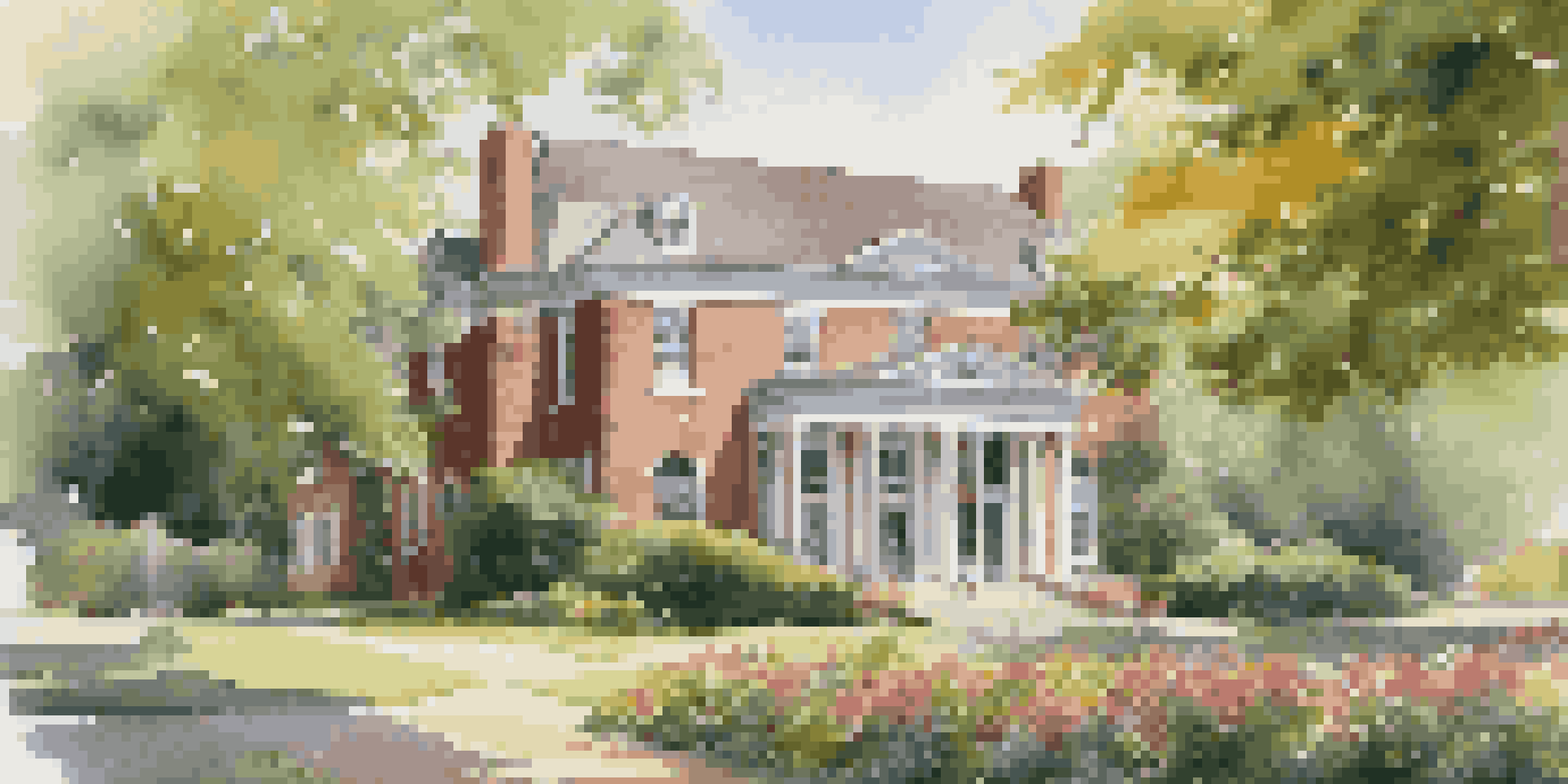 A historical county clerk office surrounded by trees and flowers, with sunlight filtering through.
