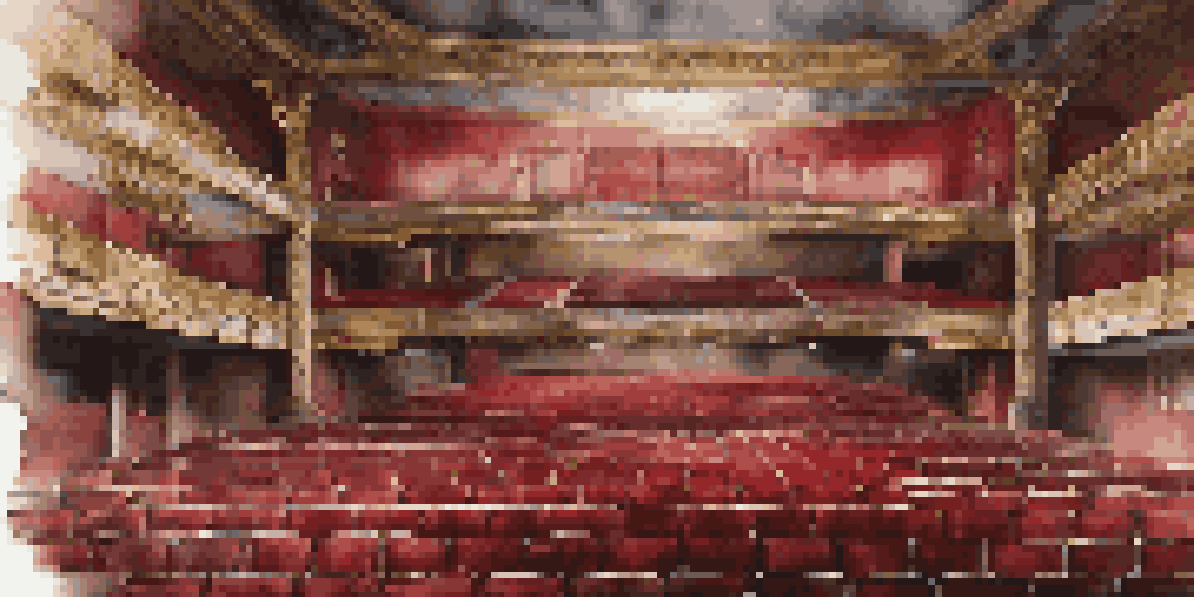 An abandoned theater with dusty beams of light illuminating its decaying interior and ornate architecture.