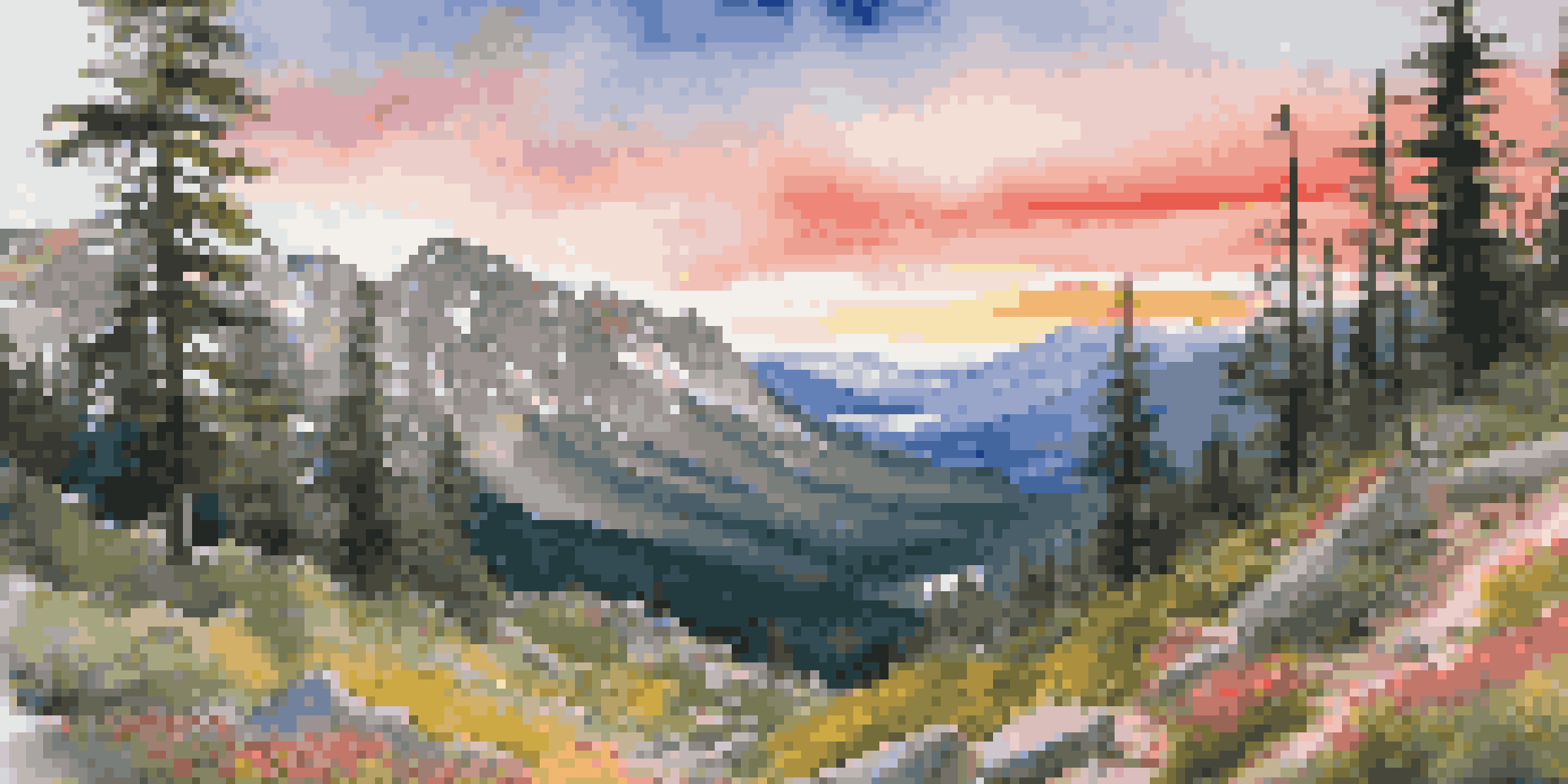 A hiker in a red jacket stands on a rocky outcrop overlooking the colorful Rocky Mountains at sunset.